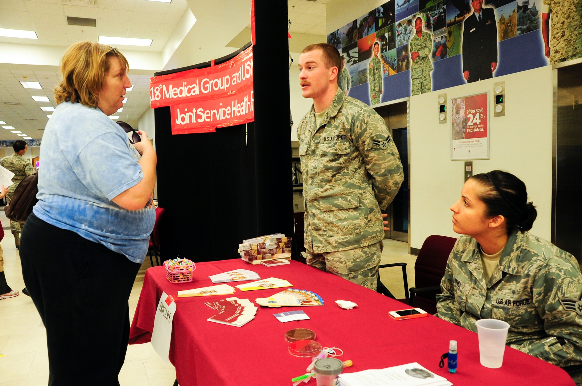 Cindy Harley, military spouse, speaks with U.S. Air Force Airman 1st Class David Buhman, 18th Medical Group TRICARE technician, and Senior Airman Taniah Otis, 18th Medical Group laboratory technician, during the Joint Services Health Promotion Fair on Kadena Air Base, Japan, Feb. 21, 2013. The health fair was the first joint service effort between Kadena and Camp Lester. There were 10 booths available inside the Exchange to answer questions and provide information on programs such as alcohol and drug abuse prevention and treatment and disease management. The Exchange also provided two televisions that displayed slides with various health facts and information. (U.S. Air Force photo/Staff Sgt. Darnell T. Cannady)