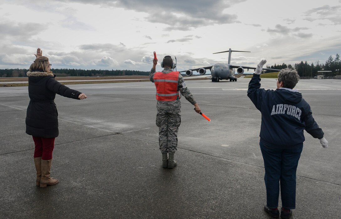 Airman 1st Class Christopher Lightfoot, 62nd Aircraft Maintenance Squadron crew chief (center), with the help of Erin Philippart (left) and Linda Moore (right), marshals McChord Field's newest C-17 Globemaster III aircraft, Feb. 20, 2013, upon the jet's initial arrival to Joint Base Lewis-McChord, Wash. Philippart and Moore are the wife and mother, respectively, of Col. Jeffrey Philippart, 62nd Airlift Wing vice commander, and the mission commander of the aircraft's delivery flight, which originated in Long Beach, Calif. (U.S. Air Force photo/Tech. Sgt. Sean Tobin)