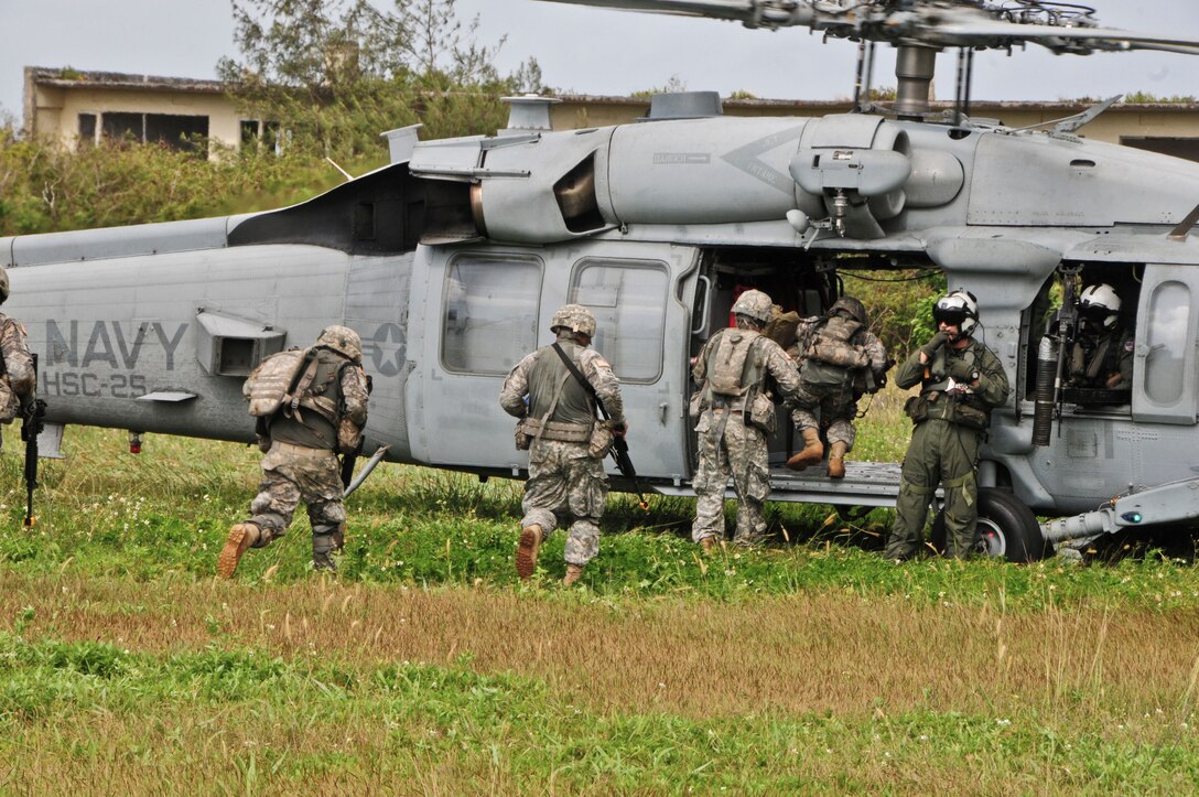 Flightcrew members from the Helicopter Sea Combat Squadron 25 guide Soldiers from the 1st Battalion, 294th Infantry Regiment, Guam Army National Guard, as they enter an MH-60S Seahawk during an extraction from a simulated combat zone at Andersen South, Guam, Feb. 19, 2013. HSC-25 was able to fulfill their training requirements on ground personnel recovery while assisting Guam Army National Guard Soldiers with their Combat Life Saver course. (U.S. Air Force photo by Airman 1st Class Marianique Santos/Released)