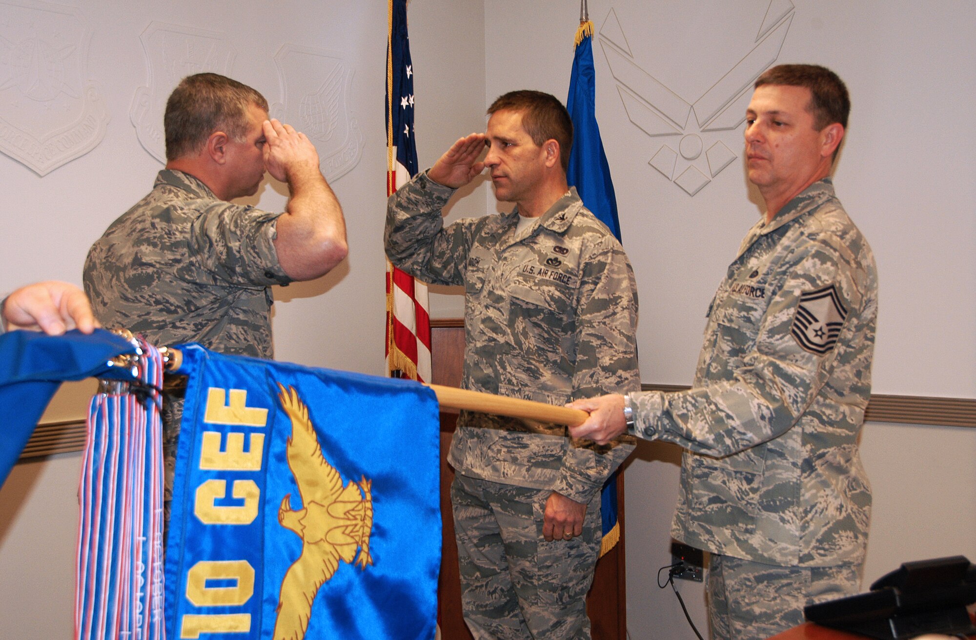 The recent historical activation ceremony for the 822nd Civil Engineer Flight was conducted in an unusual manner. The presiding officer was at Robins AFB, Ga., on speaker phone while the rest of the ceremony was being held at Naval Air Station Fort Worth Joint Reserve Base, Texas. Shown from left to right, Lt. Col. Frank Mason, proxy presiding officer faces Col. Gene Odom, 810th CEF commander, as Senior Master Sgt. Jimmy Camargo, 810th CEF's longest standing member, furls and cases the 810th flag signifying the 810th CEF's deactivation.