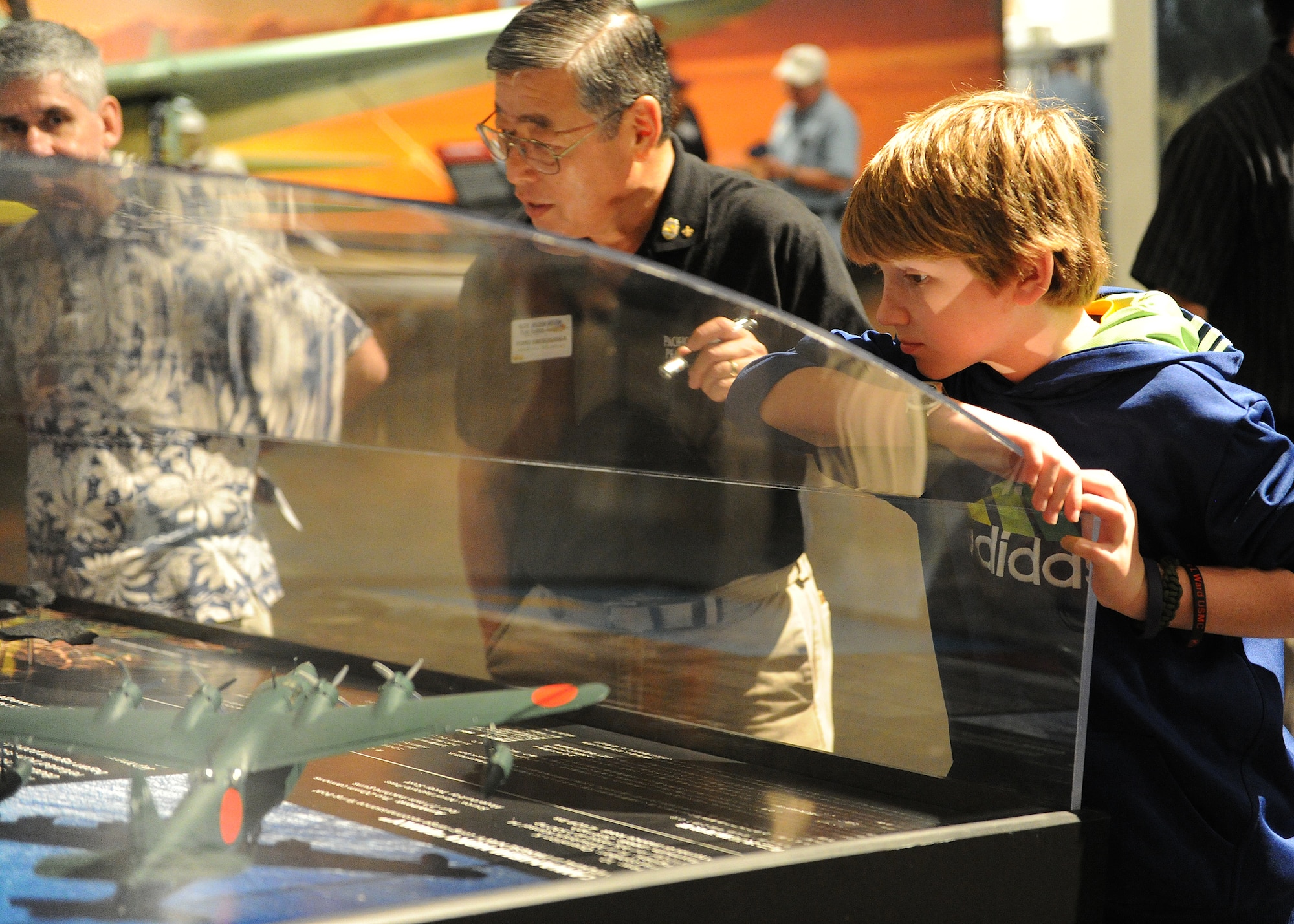 Ford Ebesugawa, tour guide (center), explains how Japanese aircraft attacked on Dec. 7, 1941 Pearl Harbor to Carl Hess, Make-A-Wish recipient (right), at the Pacific Aviation Museum, Ford Island, Hawaii, Feb. 19, 2013. Carl is fighting acute lymphoblastic leukemia (ALL), a fast-growing cancer of the white blood cells, and wished to be a downed World War II pilot. Since 1980, the MAW Foundation has changed the lives of children with life-threatening medical conditions through its wish-granting work. (U.S. Air Force photo/Tech. Sgt. Jerome S. Tayborn)