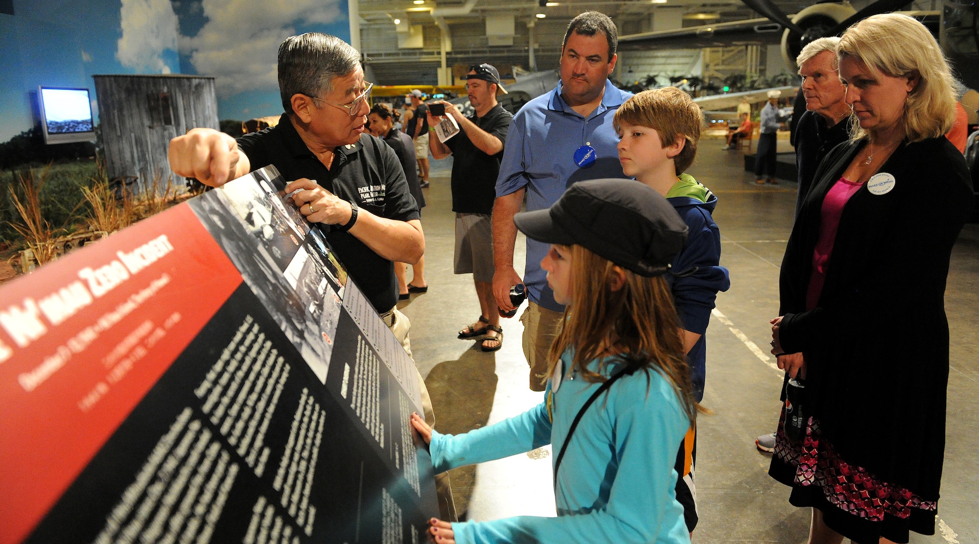 Ford Ebesugawa, tour guide (right), explains a Japanese Zero crash incident that occurred during the Dec. 7, 1941 Pearl Harbor attacks to Carl Hess, Make-A-Wish recipient (left), and his sister Kayelynn Hess (center) at the Pacific Aviation Museum, Ford Island, Hawaii, Feb. 19, 2013. Carl is fighting acute lymphoblastic leukemia (ALL), a fast-growing cancer of the white blood cells, and wished to be a downed World War II pilot. Since 1980, the MAW Foundation has changed the lives of children with life-threatening medical conditions through its wish-granting work. (U.S. Air Force photo/Tech. Sgt. Jerome S. Tayborn)