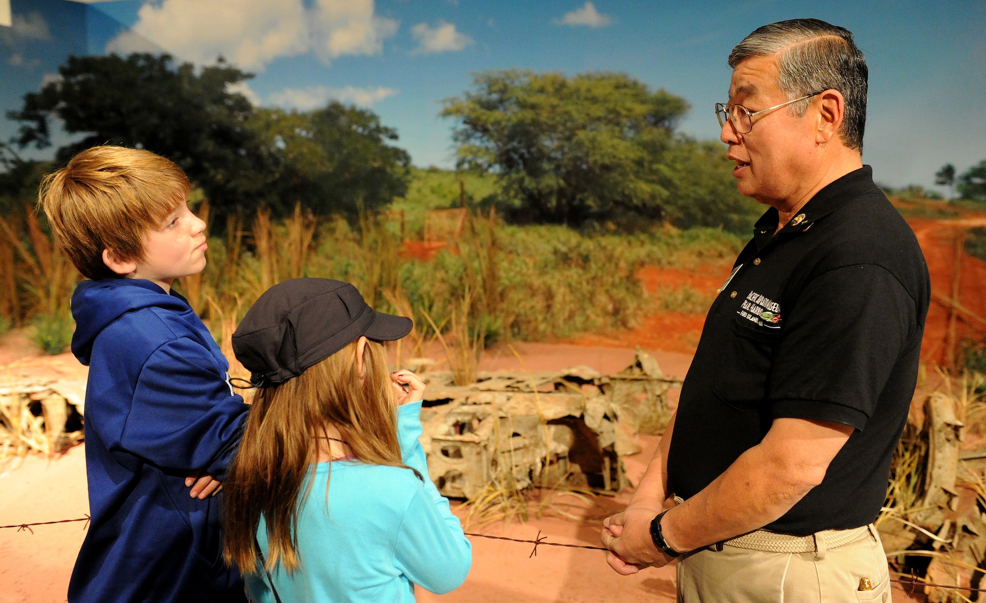 Ford Ebesugawa, tour guide (right), explains a Japanese Zero crash incident that occurred during the Dec. 7, 1941 Pearl Harbor attacks to Carl Hess, Make-A-Wish recipient (left), and his sister Kayelynn Hess (center) at the Pacific Aviation Museum, Ford Island, Hawaii, Feb. 19, 2013. Carl is fighting acute lymphoblastic leukemia (ALL), a fast-growing cancer of the white blood cells, and wished to be a downed World War II pilot. Since 1980, the MAW Foundation has changed the lives of children with life-threatening medical conditions through its wish-granting work. (U.S. Air Force photo/Tech. Sgt. Jerome S. Tayborn)