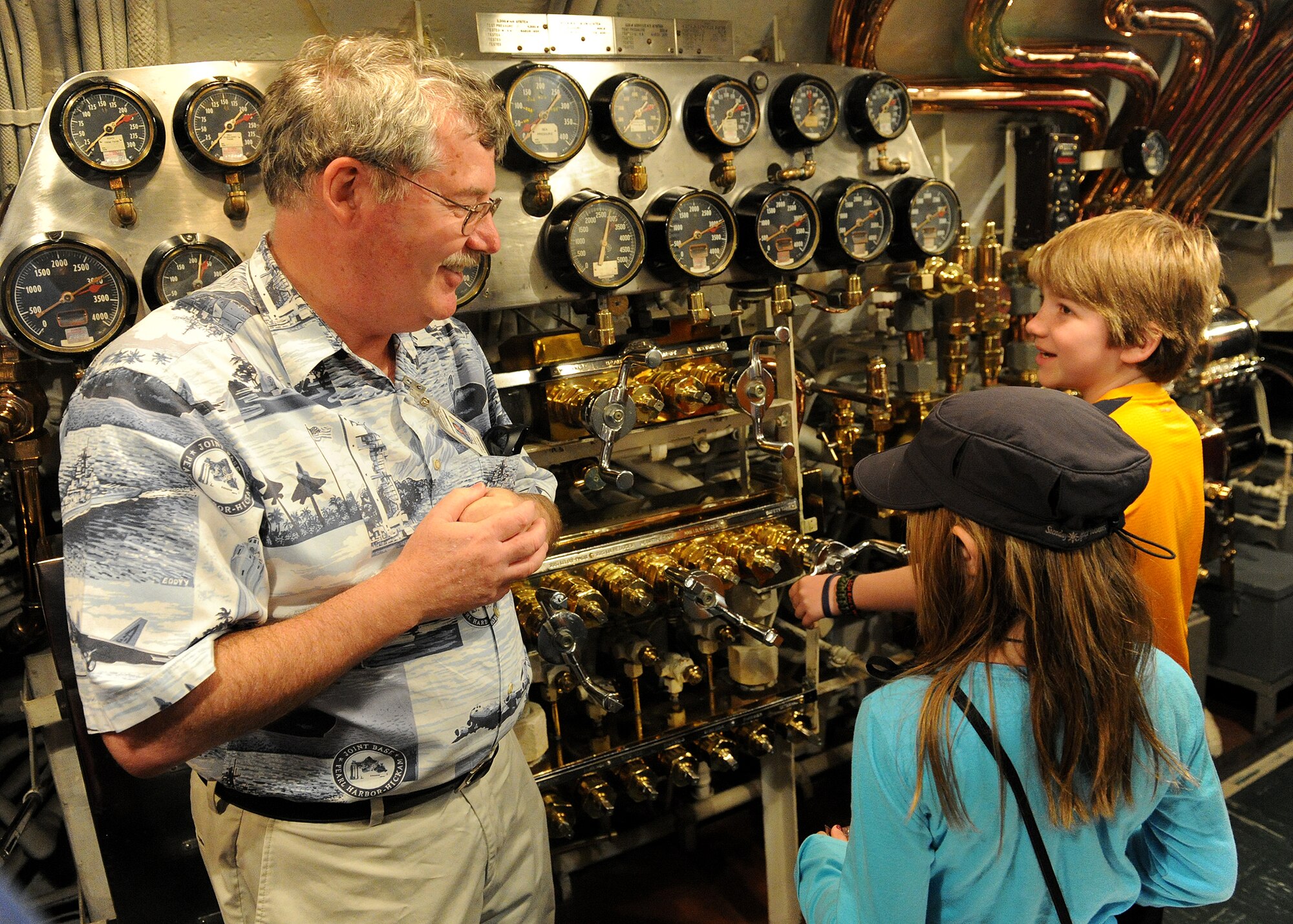 Charles Hinman, USS Bowfin, education director (left) explains the control panels aboard the USS Bowfin to Carl Hess (right), Make-A-Wish recipient, and his sister Kayelynn Hess (center), near Ford Island, Hawaii, Feb. 19, 2013. Carl is fighting acute lymphoblastic leukemia (ALL), a fast-growing cancer of the white blood cells, and wished to be a downed World War II pilot. During his visit he received a rare opportunity to spend the night aboard the USS Missouri, fly in a bi-plane, and tour various historical WWII sites. (U.S. Air Force photo/Tech. Sgt. Jerome S. Tayborn)