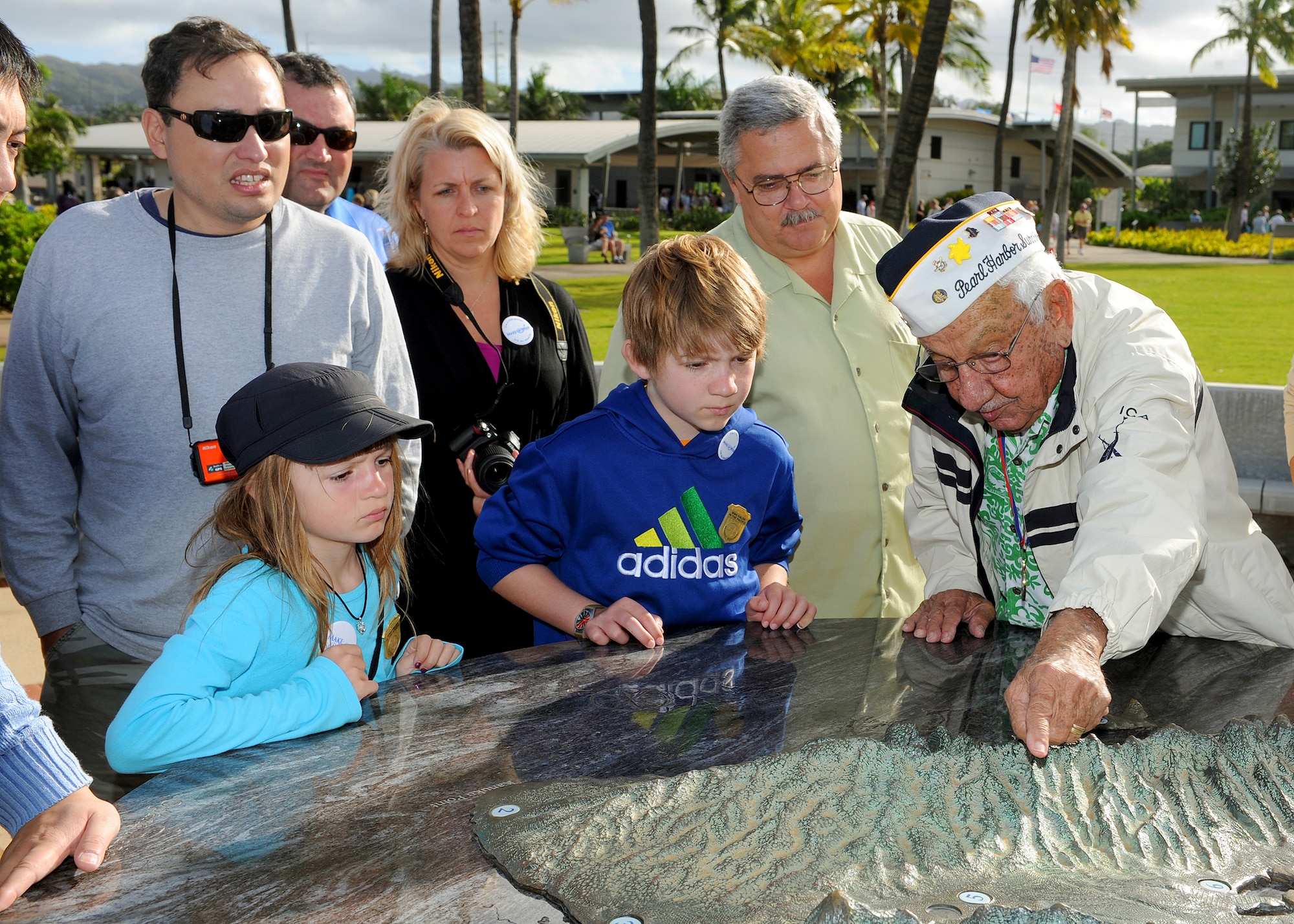 Pearl Harbor attacks survivor, Alfred Benjamin Kame’eiamoku Rodrigues, US Navy (retired) (right) explains the Dec. 7, 1941 attacks on Pearl Harbor to Carl Hess, Make-A-Wish recipient (center), Carl’s sister Kayelynn Hess, his parents James and Heidi Sullivan, and bystanders (far left) at the USS Arizona Memorial, near Ford Island, Hawaii, Feb. 19, 2013. Carl is fighting acute lymphoblastic leukemia (ALL), a fast-growing cancer of the white blood cells, and wished to be a downed World War II pilot.  During his visit he received a rare opportunity to spend the night aboard the USS Missouri, fly in a bi-plane, and tour various historical WWII sites. (U.S. Air Force photo/Tech. Sgt. Jerome S. Tayborn)