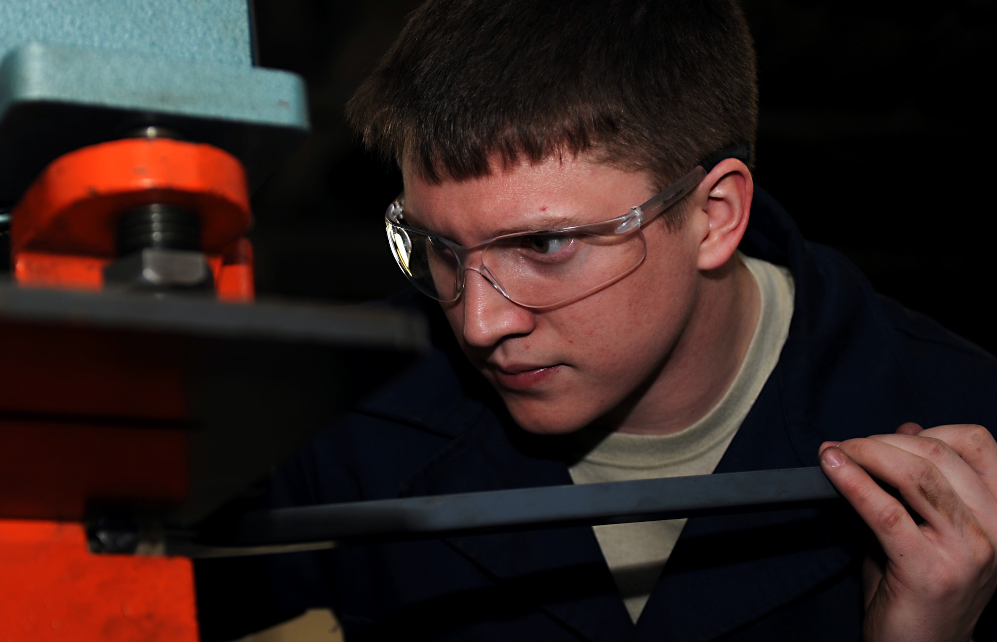 U.S. Air Force Airman 1st Class Spencer Chambers, 1st Maintenance Squadron Metals Technology aircraft metals technologist, uses a machine to punch a hole in a piece of metal at Langley Air Force Base, Va., Feb. 19, 2013. In this shop, there is always something new or different to work on, giving these Airmen plenty of chances to get creative, while cost-effectively supporting the Langley mission. (U.S. Air Force photo by Senior Airman Teresa Aber/Released)