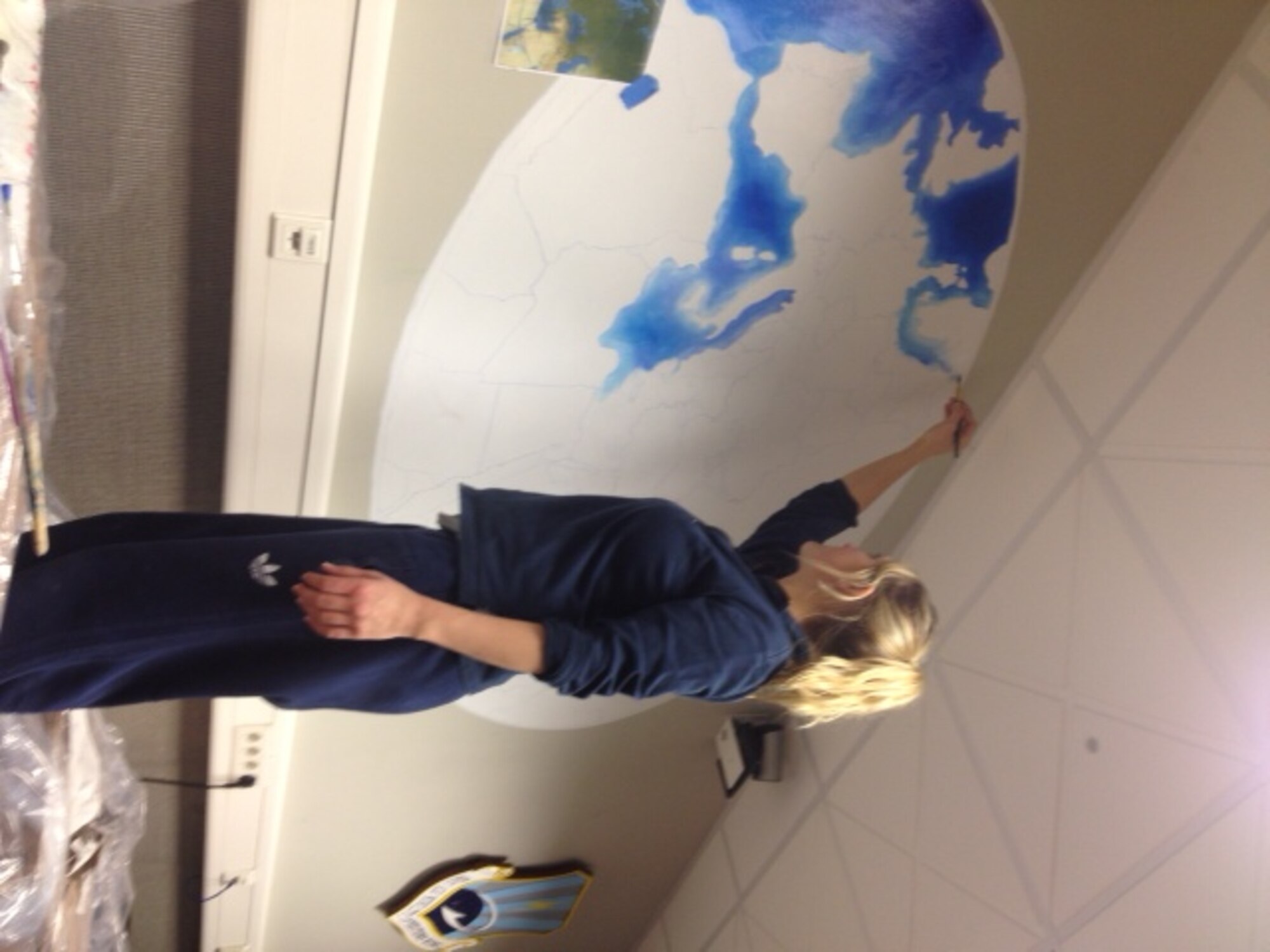 First Lt. Nicole Mancos, 721st Aerial Port Squadron air terminal operations flight commander, paints a mural for the 521st Air Mobility Operations Wing heritage room at the Kisling NCO Academy on Kapaun Air Station, Germany. The heritage room was completed Feb. 15, 2013 by four volunteers from the 521st AMOW. (Courtesy photo)