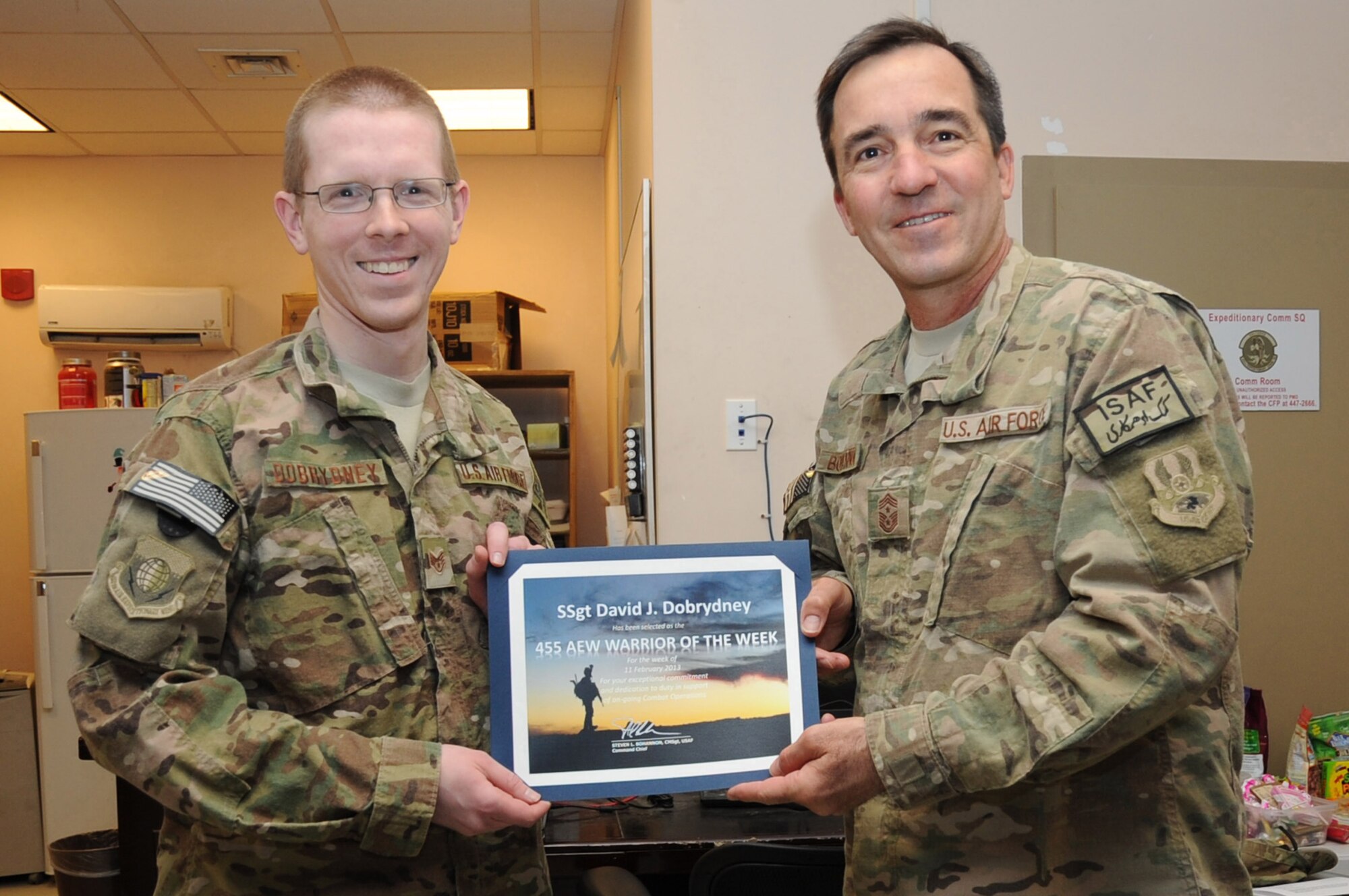 Chief Master Sgt. Steve Bohannon, Command Chief Master Sergeant of the 455th Air Expeditionary Wing, presents the "Warrior of the Week" award to Staff Sgt. David Dobrydney, 455th Air Expeditionary Wing Public Affairs staff writer, on Bagram Airfield, Afghanistan, Feb. 18, 2013. Dobrydney is responsible for maintaining the official Bagram website and newsletter. (U.S. Air Force photo/Master Sgt. Jun Kim)