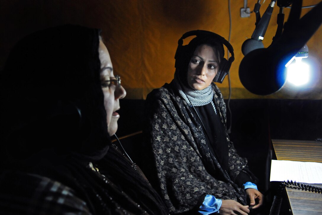 Nargas Karimi, right, a broadcast journalist with Radio Television Afghanistan in Farah City, listens to a response from Leiluma Sediqui, left, Farah director of women's affairs, during a live radio broadcast in Farah City, Afghanistan, Feb. 23, 2013.