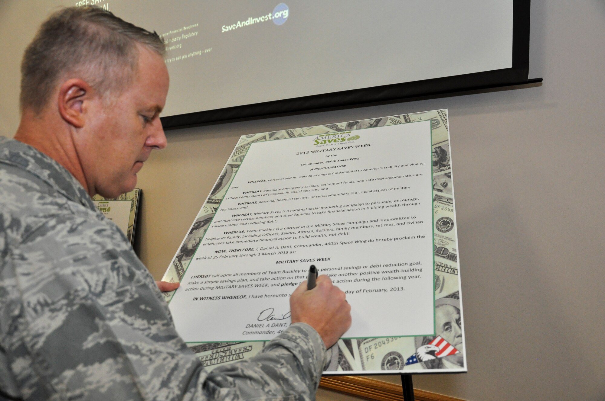 Col. Dan Dant, 460th Space Wing commander, signs the pledge starting Military Saves Week Feb. 26, 2013, at Bldg. 606 on Buckley Air Force Base, Colo.  The week is scheduled to include seminars and training on all varieties of financial matters. (U.S. Air Force photo by Staff Sgt. Nicholas Rau/Released)