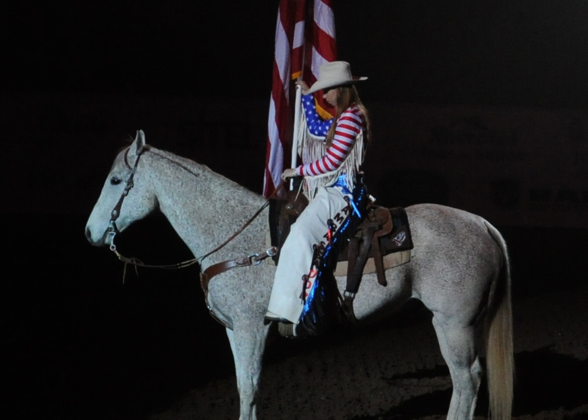 SAN ANGELO, Texas – A San Angelo Stock Show and Rodeo ambassador presents the American Flag at the beginning of the San Angelo Stock Show and Rodeo’s Military Appreciation Night at the Foster Communication Coliseum, Feb. 20. While the flag was presented, Patriotic Blue sang the National Anthem. (U.S. Air Force photo/ Staff Sgt. Laura McFarlane)