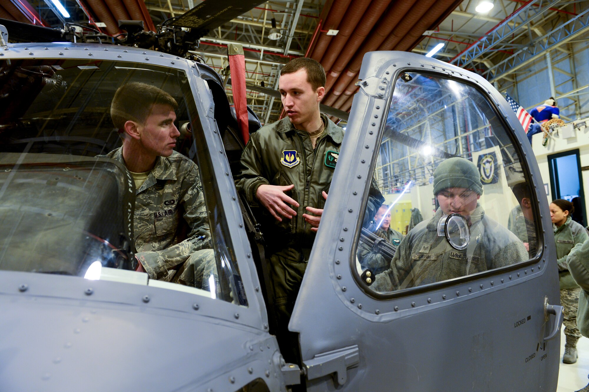 ROYAL AIR FORCE LAKENHEATH, England – Capt. Mark Fraser (center), 56th Rescue  Squadron HH-60G Pave Hawk pilot, explains how the HH-60 operates to Senior Airmen Daniel Bigham (left), 100th Operations Support Squadron aviation resource manager from RAF Mildenhall, and Patrick Guerin, 48th Munitions Squadron conventional maintenance crew chief, during the  48th Operations Group immersion Feb. 22, 2013. The Airmen visited different squadrons within the group to see the 48th OG mission firsthand. (U.S. Air Force photo by Staff Sgt. Stephanie Mancha)