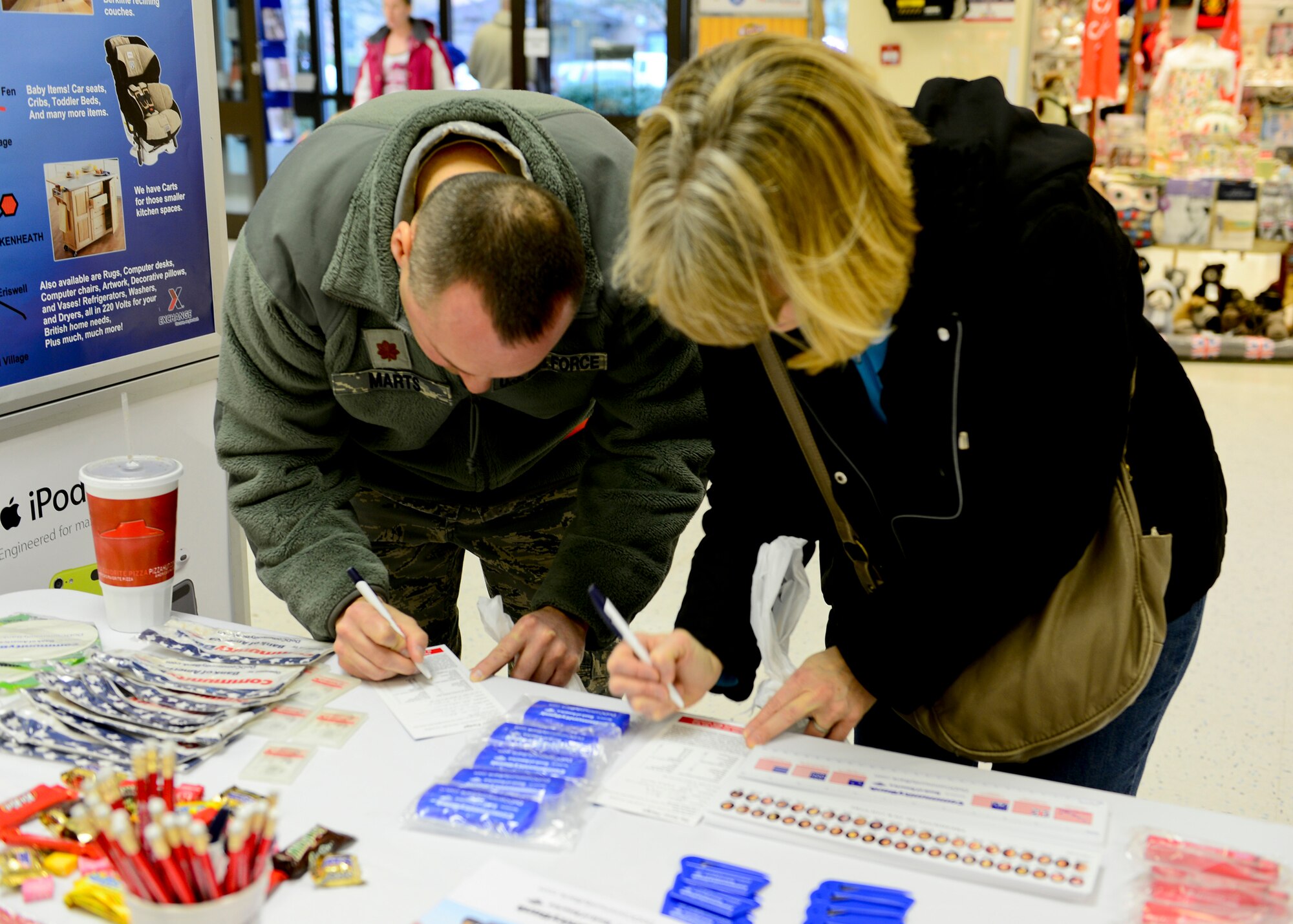 ROYAL AIR FORCE LAKENHEATH, England – Maj. Sean Martin, 48th Inpatient Care Squadron medical multi-service unit flight commander, and his wife Jackie sign the “Saver Pledge” during Military Saves Week Feb. 25, 2013. The RAFL Airman and Family Readiness Center and Community Bank setup informational booths around base to encourage military families to take the pledge and start saving money each month. (U.S. Air Force photo by Staff  Sgt. Stephanie Mancha)