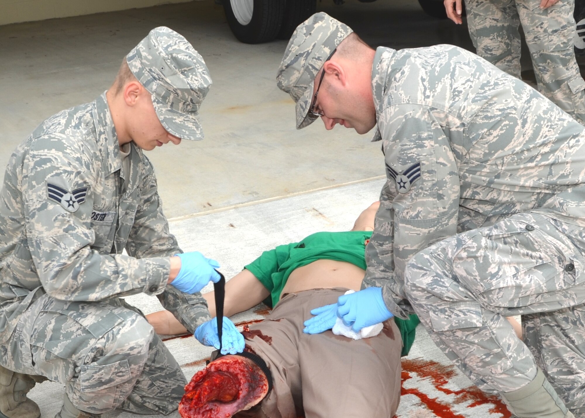 Senior Airman Christopher Frost, left, applies a tourniquet while Senior Airman Donald Davenport uses direct pressure to try to staunch blood loss on a Multiple Amputation Trauma Trainer Jan. 29, 2013, in the ambulance bay outside the Keesler Medical Center emergency room, Keesler Air Force Base, Miss.  Both Airmen are 81st Medical Operations Squadron Emergency Services Flight medical technicians.  Matt is a training tool that contains approximately six liters of blood, just like an adult human to help first responders practice realistic emergency care.  (U.S. Air Force photo by Steve Pivnick)