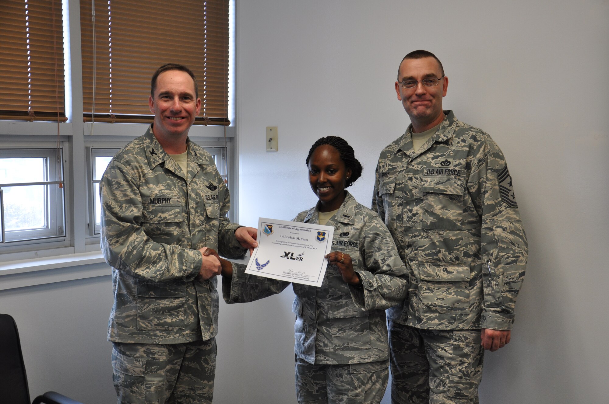 First Lt. Fiona Pham, 47th Mission Support Group logistics readiness division operations officer, poses with Col. Tom Murphy, 47th Flying Training Wing commander and Chief Master Sgt. Garry Berry, 47th FTW command chief, after being presented the XLer of the week award at Laughlin Air Force Base, Texas, Feb. 20, 2013. The XLer is a weekly award chosen by wing leadership and given to those who consistently make outstanding contributions to Laughlin and their unit. (U.S. Air Force photo/2nd Lt. Evan Ross)