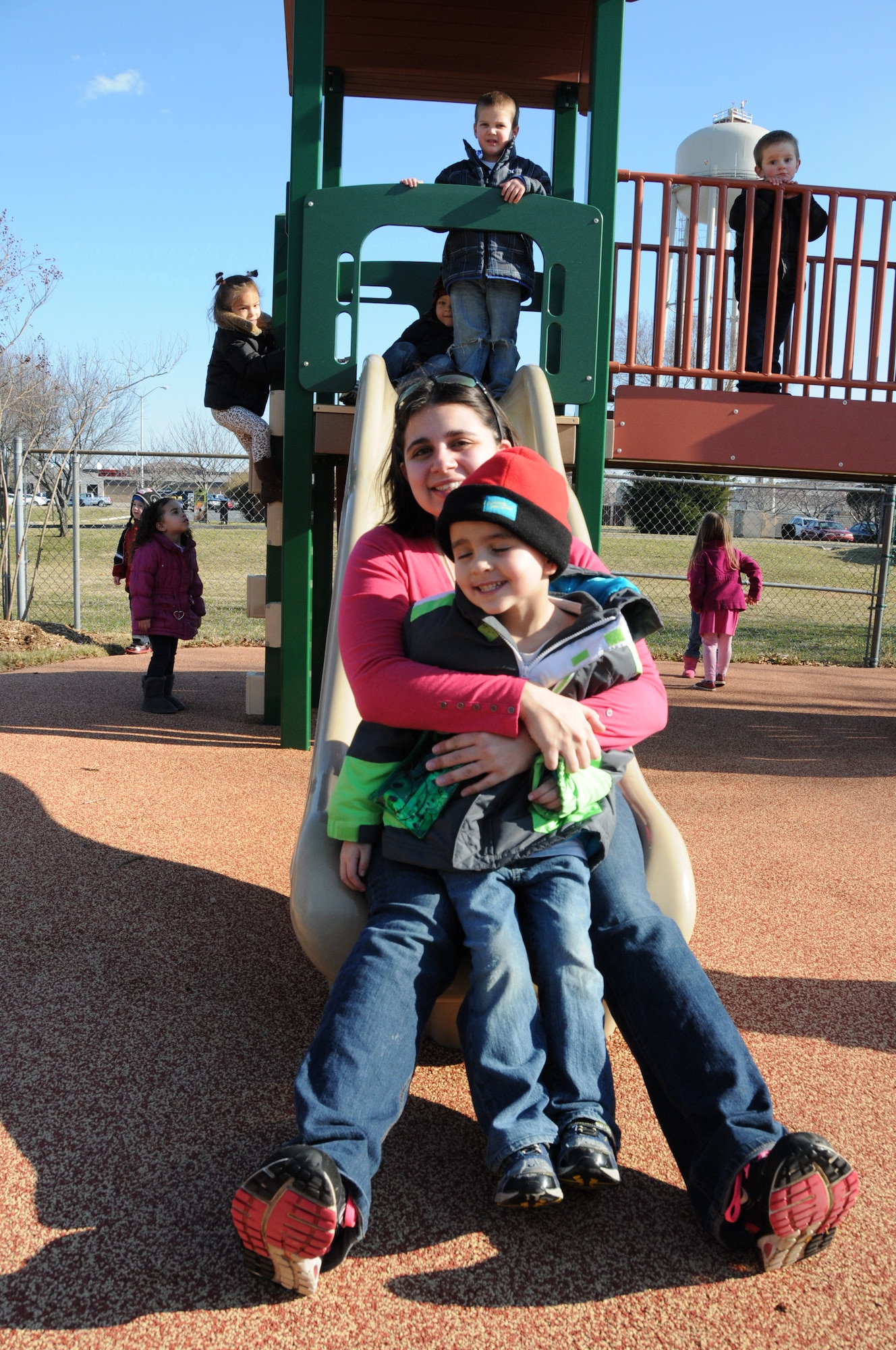 Kyle, 5, and his mother Staff Sgt. Danielle Struss, Armed Forces Medical Examiner System, are all smiles after a trip down the slide Feb. 15, 2013, following a ribbon cutting ceremony which officially opened the new and improved playground for preschoolers at the Child Development Center, Dover Air Force Base, Del. In addition to slides and swings, the new playground area features outdoor musical instrument stations and a dramatic stage. (U.S. Air Force photo/Master Sgt. Veronica Aceveda)