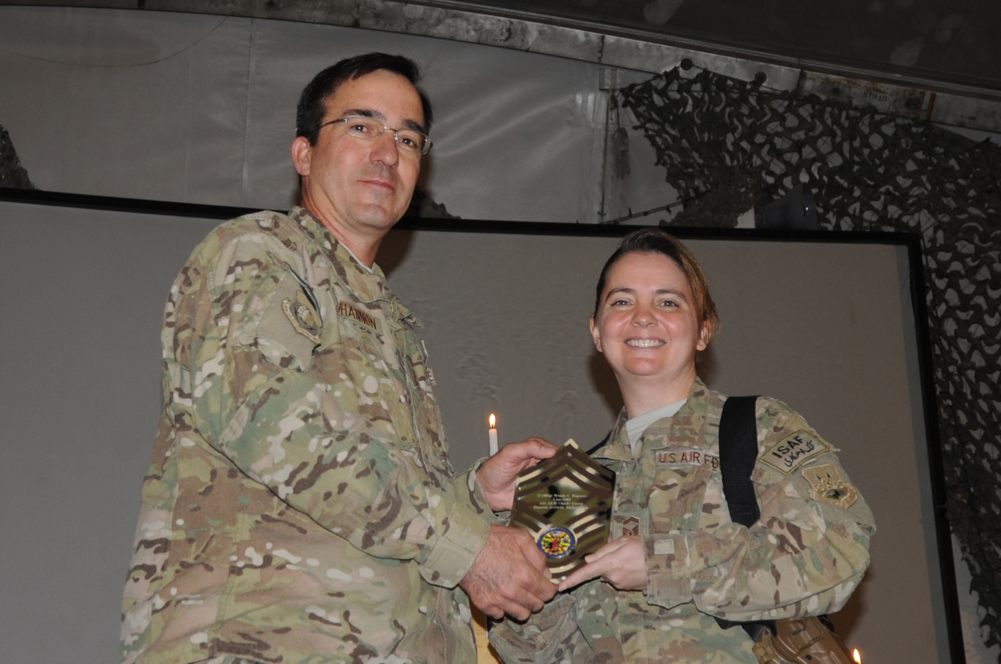 Senior Master Sgt. Wendy Ragnone, 455th Expeditionary Maintenance Squadron lead production superintendent, receives a memento from 455th Air Expeditionary Wing Command Chief Master Sgt. Steven Bohannon at the chief master sergeant induction ceremony on Bagram Airfield, Afghanistan, Feb. 24, 2013. Ragnone has been selected for promotion to the Air Force's highest enlisted rank. (U.S. Air Force photo/Staff Sgt. David Dobrydney)