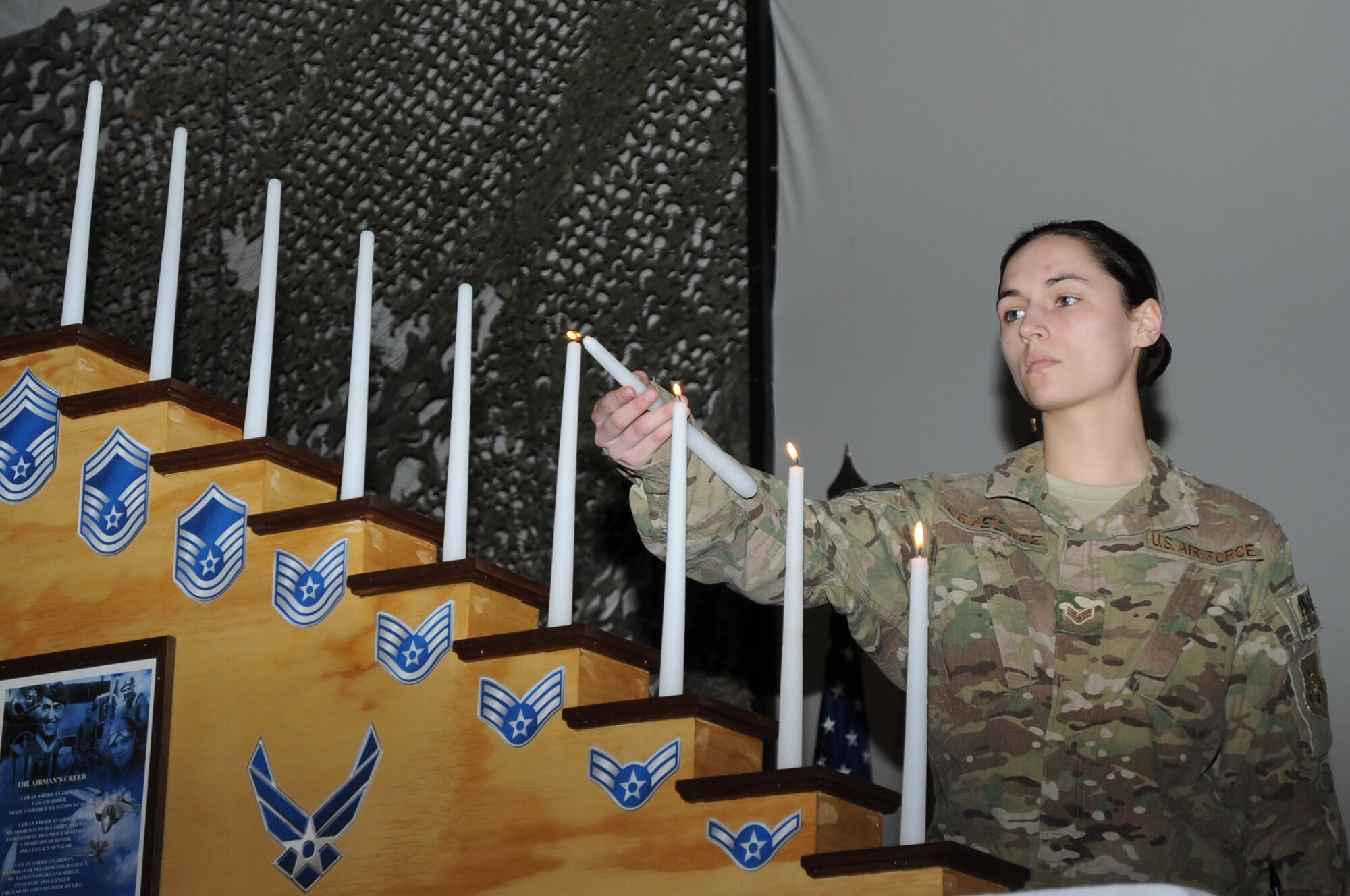 Senior Airman Ashley Lovelace, 455th Expeditionary Operations Support Squadron intelligence specialist, lights a candle representing her enlisted rank at the chief master sergeant induction ceremony on Bagram Airfield, Afghanistan, Feb. 24, 2013. Three members of the 455th AEW were recognized for their selection for promotion to the Air Force's highest enlisted rank. (U.S. Air Force photo/Staff Sgt. David Dobrydney)