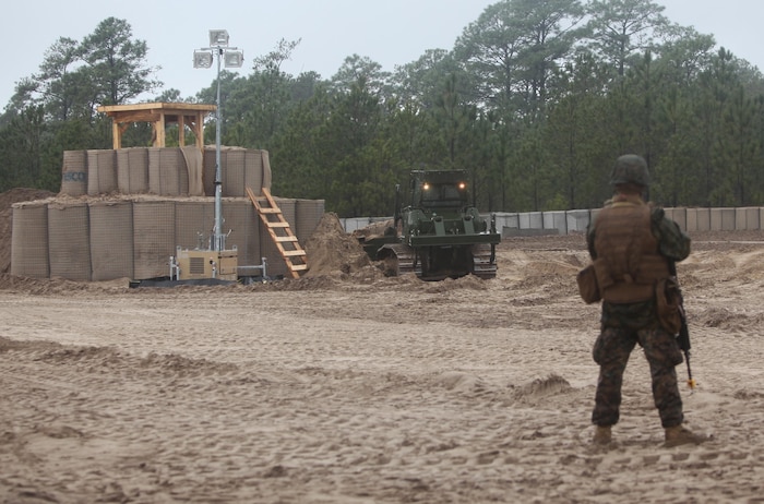 A Marine with Engineer Company, Combat Logistics Battalion 6, 2nd Marine Logistics Group stands watch as a bulldozer demolishes the unit’s patrol base during a training exercise aboard Camp Lejeune, N.C., Feb. 26, 2013. The company’s field operation centered around the construction, use and deconstruction of a forward operating base in preparation for the unit’s upcoming deployment. 