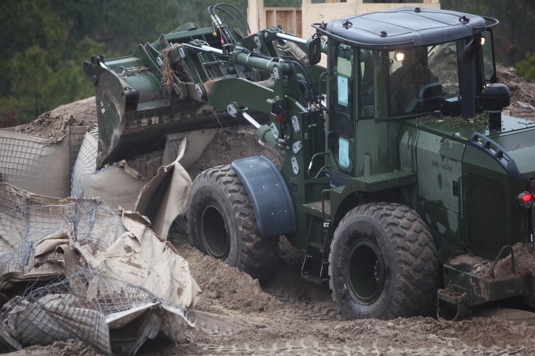 A front-end loader belonging to  Engineer Company, Combat Logistics Battalion 6, 2nd Marine Logistics Group demolishes guard towers at a forward operating base near the end of a training exercise aboard Camp Lejeune, N.C., Feb. 26, 2013. Heavy equipment operators assisted combat engineers in constructing a patrol base within 48 hours and then destroyed it several days later to prepare for the company’s upcoming deployment operations.  