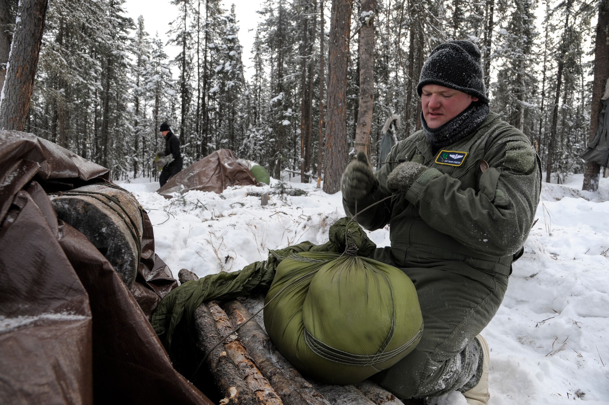 U.S Air Force Staff Sgt. Vance Streeter, 210th Rescue Squadron aerial gunner, constructs a door plug for his shelter Feb. 21, 2013, Eielson Air Force Base, Alaska.  The plug, when set properly, prevents the cold from entering the shelter and can help keep the internal warmth at a level well above outdoor temperatures.  (U.S. Air Force Photo/Airman 1st Class Peter Reft)