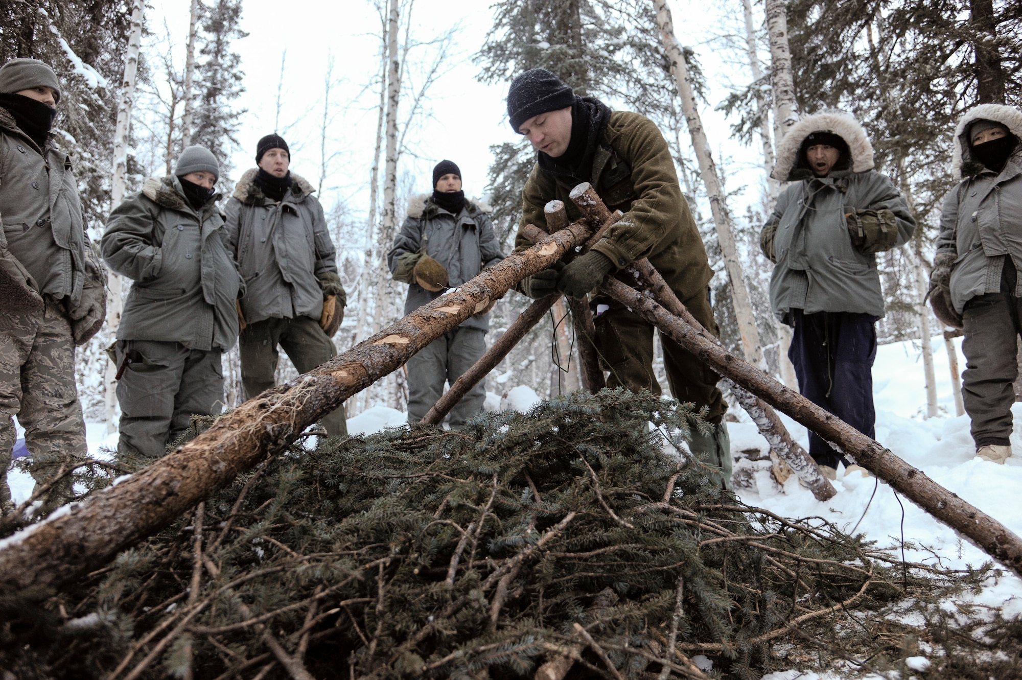 U.S. Air Force Staff Sgt. Justin Carson, Det. 1, 66th Training Squadron Survival Evasion Resistance Escape specialist, demonstrates to U.S. military service members the construction of a thermalized A-frame shelter Feb. 21, 2013, Eielson Air Force Base, Alaska.  Carson is tasked with providing arctic survival training to U.S. military and allies from around the globe, including Danish and Australian forces.  (U.S. Air Force Photo/Airman 1st Class Peter Reft)