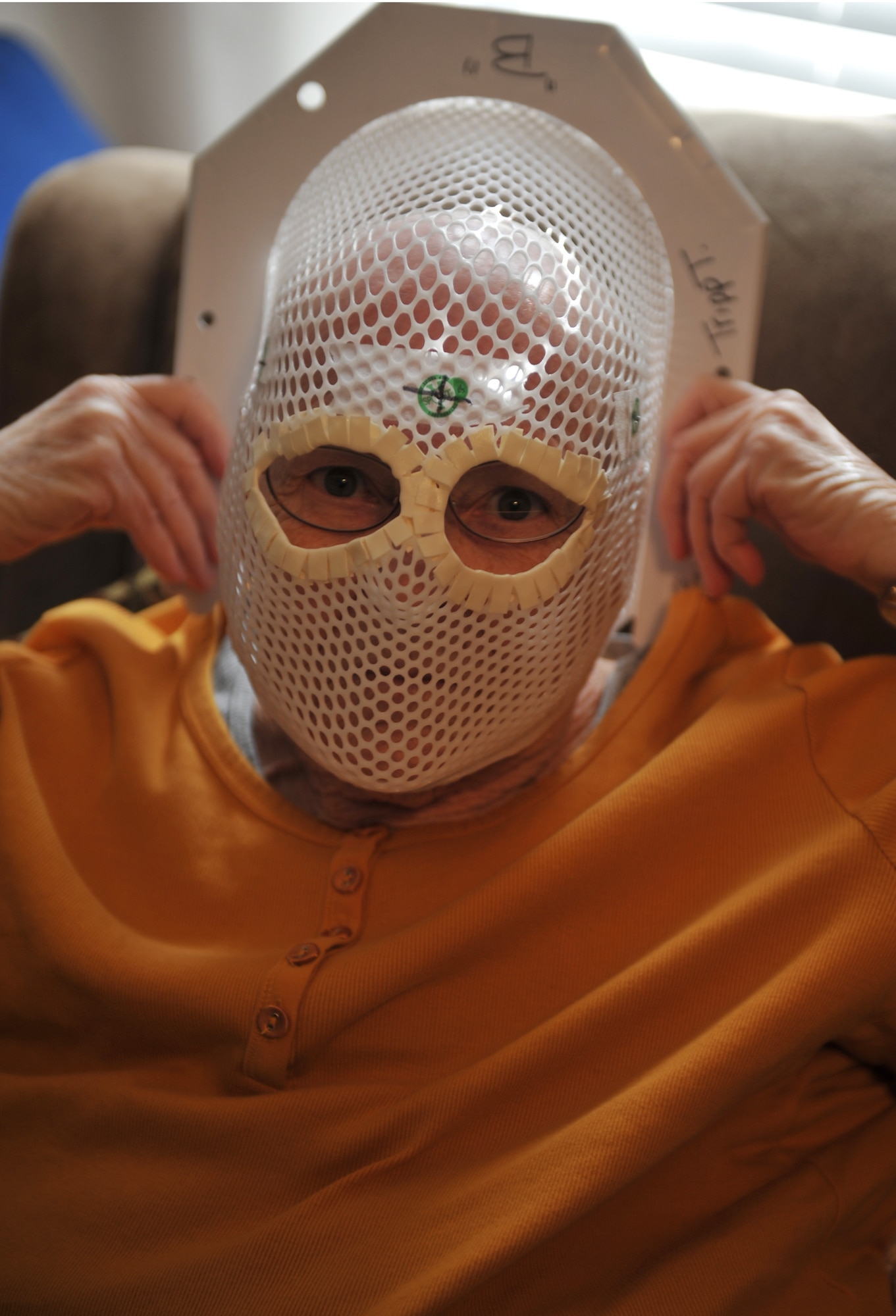 KNOB NOSTER, Mo. -- June Tripp, small cell cancer survivor, demonstrates the radiation mask she used during her radiation therapy, Feb. 19. June endured 15 days of radiation treatments to help shrink tumors and kill cancer cells. (U.S. Air Force photo/Heidi Hunt)