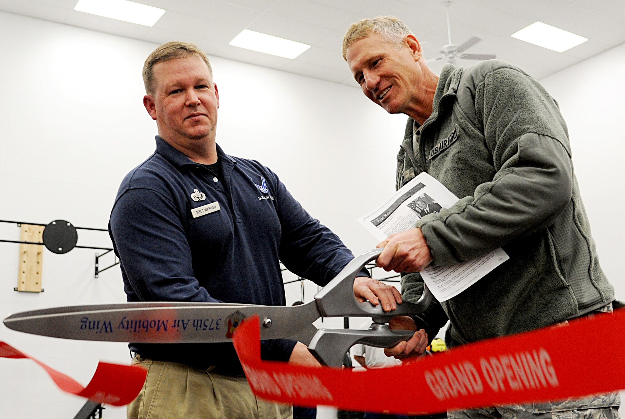 Master Sgt. Wade Washom, 375th Force Support Squadron fitness center superintendent, and Col. David Almand, 375th Air Mobility Wing commander, cut the ribbon on the new high intensity training room during a grand opening tour Feb. 20. The James Sports Center recently completed construction on the new room geared toward a high intensity workout that patrons were unable to perform previously. The room also has a contained children's play area with playground equipment, children's cardio machines and an entertainment center.  (U.S. Air Force photo/ Senior Airman Tristan English)