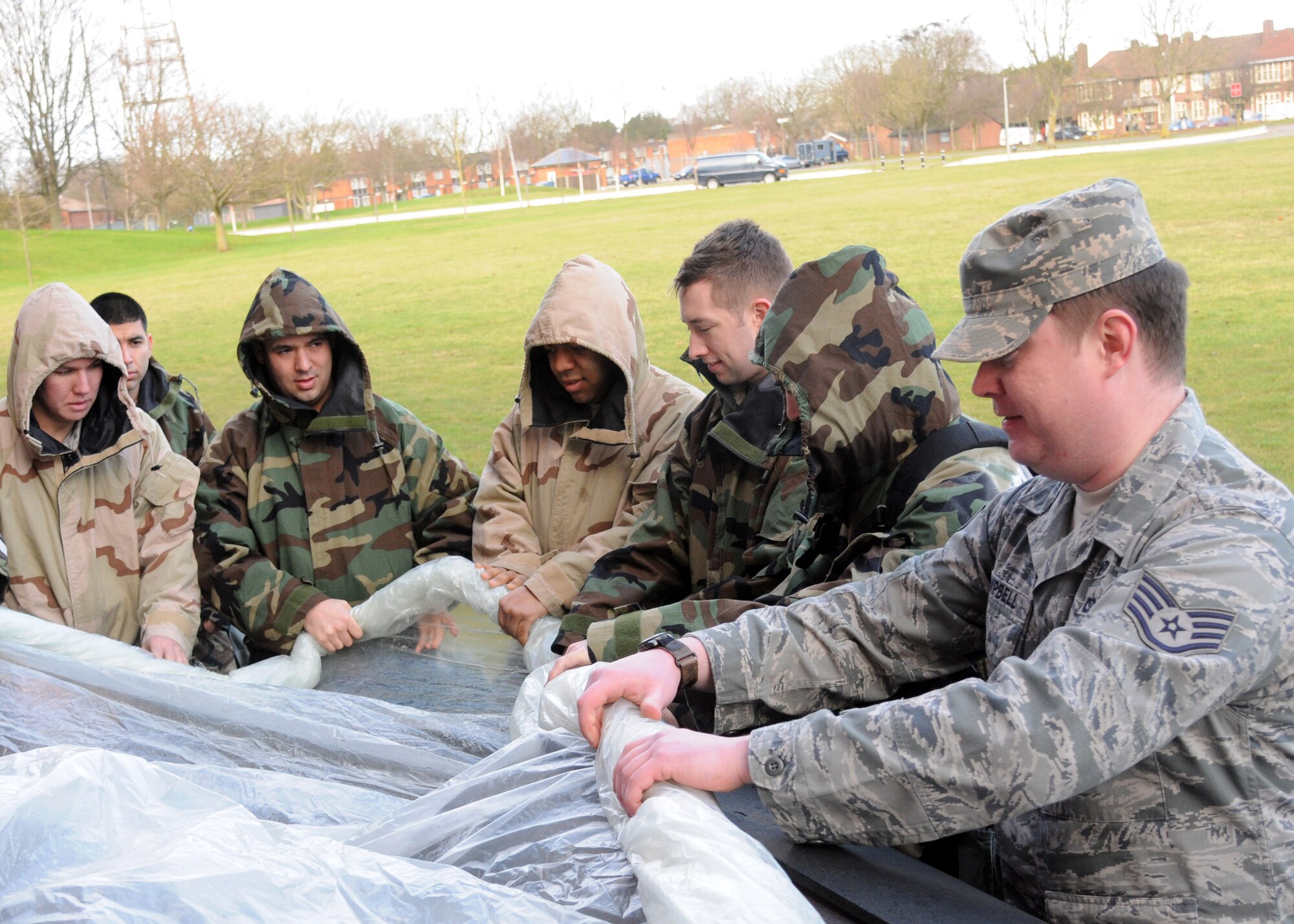 Airmen simulate decontaminating a piece of equipment during chemical, biological, radiological and nuclear training Feb. 7, 2013, outside building 680 at RAF Mildenhall, England. Students also learned how to properly don their mission-oriented protective posture suits and their inspect gas masks. (U.S. Air Force photo by Airman 1st Class Kelsey Waters/Released)