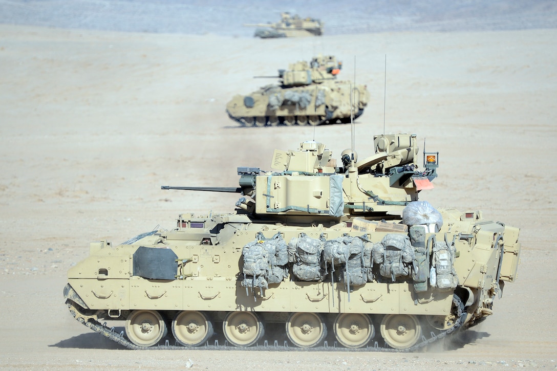 A M1-A1 Abrams tank and M2 Bradley fighting vehicles conduct a bounding overwatch maneuver during a training mission at the National Urban Warfare Center in the Mojave Desert at the National Training Center on Fort Irwin, Calif., Feb. 21, 2013.