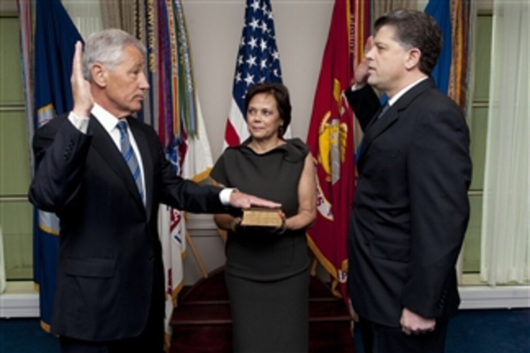 Lilibet Hagel, center, holds the Bible for her husband Chuck Hagel, left, as he is sworn into office as the 24th Secretary of Defense by DoD Director of Administration and Management Michael L. Rhodes, right, in the Pentagon on Feb. 27, 2013.  