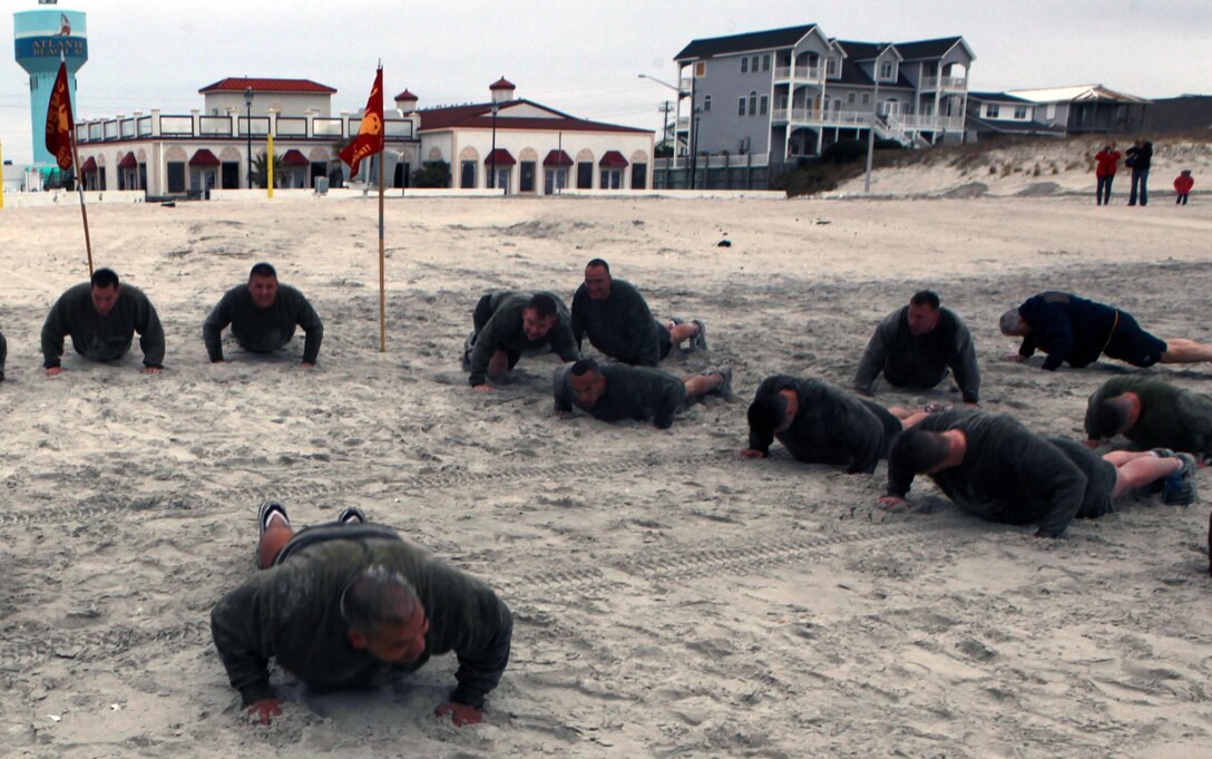 Lt. Col. Jaime L. Gutierrez, front, commanding officer of the Center for Naval Aviation Technical Training Marine Unit Cherry Point, leads his instructors and staff in push-ups at Atlantic Beach before plunging into the ocean Feb. 22.