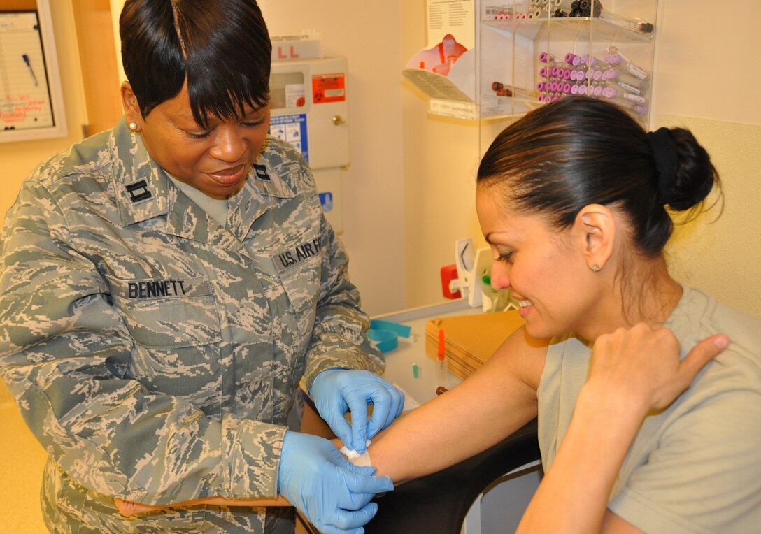 Capt. Peggy Bennett applies a band-aid to Staff Sgt. Alicia Yi, after taking a blood sample at the Scott Air Force Base clinic.  Medical specialists perform these and other lab-related tasks every UTA to ensure reservists maintain their medical readiness. Bennett is assigned to the 932nd Medical Squadron and Yi to the 932nd Aeromedical Staging Squadron. (U.S. Air Force photo/Tech. Sgt. Dan Oliver)  