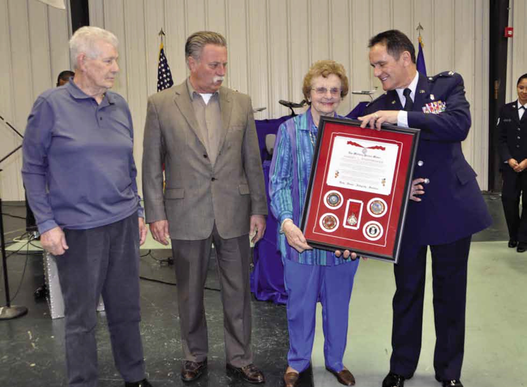Col. Robert Weisenberger, 452d Medical Group commander, presents the Military Parent Award to his mother Harriet, a Navy nurse during WWII, Sunday, Feb. 24, 2013, at his retirement ceremony in the March Field Air Museum. Joining her for the presentation are his older brothers, Jim, a combat Marine veteran during Vietnam standing next to Harriet, and Paul, who served in the Army during the Korean war. (U.S. Air Force photo by Staff Sgt. Carrie Peasinger)