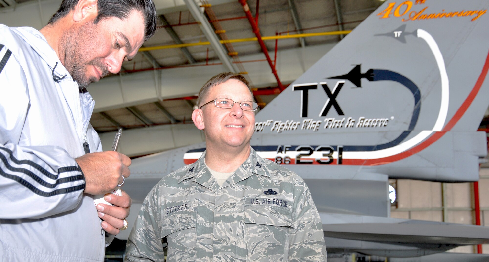 Former Texas Ranger baseball player, Benji Gil, visited the Naval Air Station Fort Worth Joint Reserve Base, Texas, today and stopped to visit the Air Force Reservists at the 301st Fighter Wing. Benji is seen here signing a baseball for Col. Max Stitzer, 301st Maintenance Group commander. Benji played with the Texas Ranger from 1993 to 1997 and then went on to win a championship ring in 2003 with the Anaheim Angels. (U.S. Air Force photo/Master Sgt. Julie Briden-Garcia)