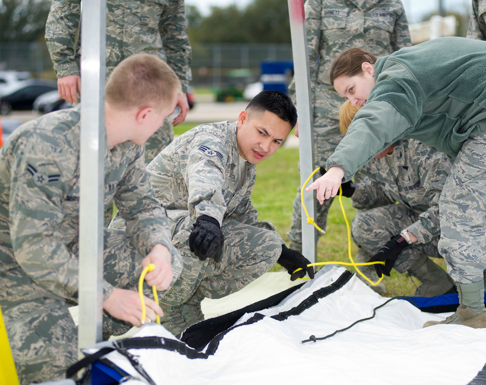 Airman 1st Class Brennan Roberts, 81st Medical Operations Squadron, receives direction from Senior Airman Jorge Panama, 81st Medical Support Squadron, and Capt. Rebekah Carlisle, 81st MDOS, on how to secure the end flap of a temporary medical facility during a base exercise Feb. 27, 2013, at Keesler Air Force Base, Miss.  The scenario included a series of biological attacks in which numerous Keesler personnel became infected and the medical group had to distribute large quantities of medicine to efficiently minimize risk.  (U.S. Air Force photo by Adam Bond)