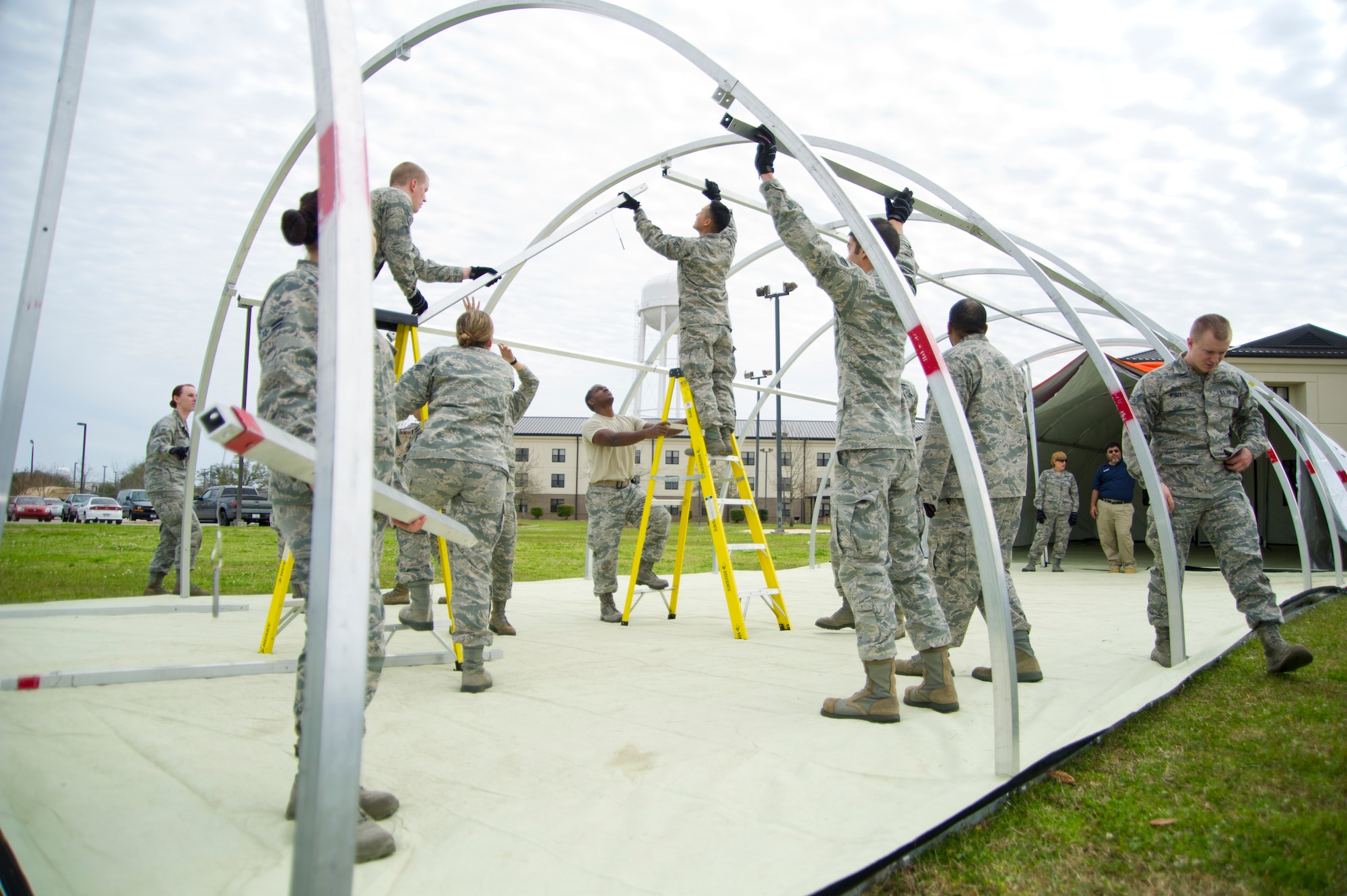 Members of the 81st Medical Group construct temporary medical facilities in response to a disease containment plan and point of dispensing exercise scenario Feb. 27, 2013, near the Vandenburg Community Center, Keesler Air Force Base, Miss.  The scenario included a series of biological attacks in which numerous Keesler personnel became infected and the medical group had to distribute large quantities of medicine to efficiently minimize risk.  (U.S. Air Force photo by Adam Bond)