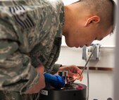Tech Sgt. Jason Truong, 47th Flying Training Wing Precision Measurement Equipment Laboratory lab chief NCO in charge, uses a flashlight and mirror to read the serial number on an accelerometer calibrator, at the PMEL shop on Laughlin Air Force Base, Texas, Feb. 26, 2013. The accelerometer calibrator measures vibrations and serial numbers are checked to ensure each part is matched to a specific machine so measurements are consistent. PMEL technicians work to ensure that measurement equipment ranging from scales at the base gym to aircraft gauges provide accurate information.  (U.S. Air Force photo/Senior Airman Nathan Maysonet)