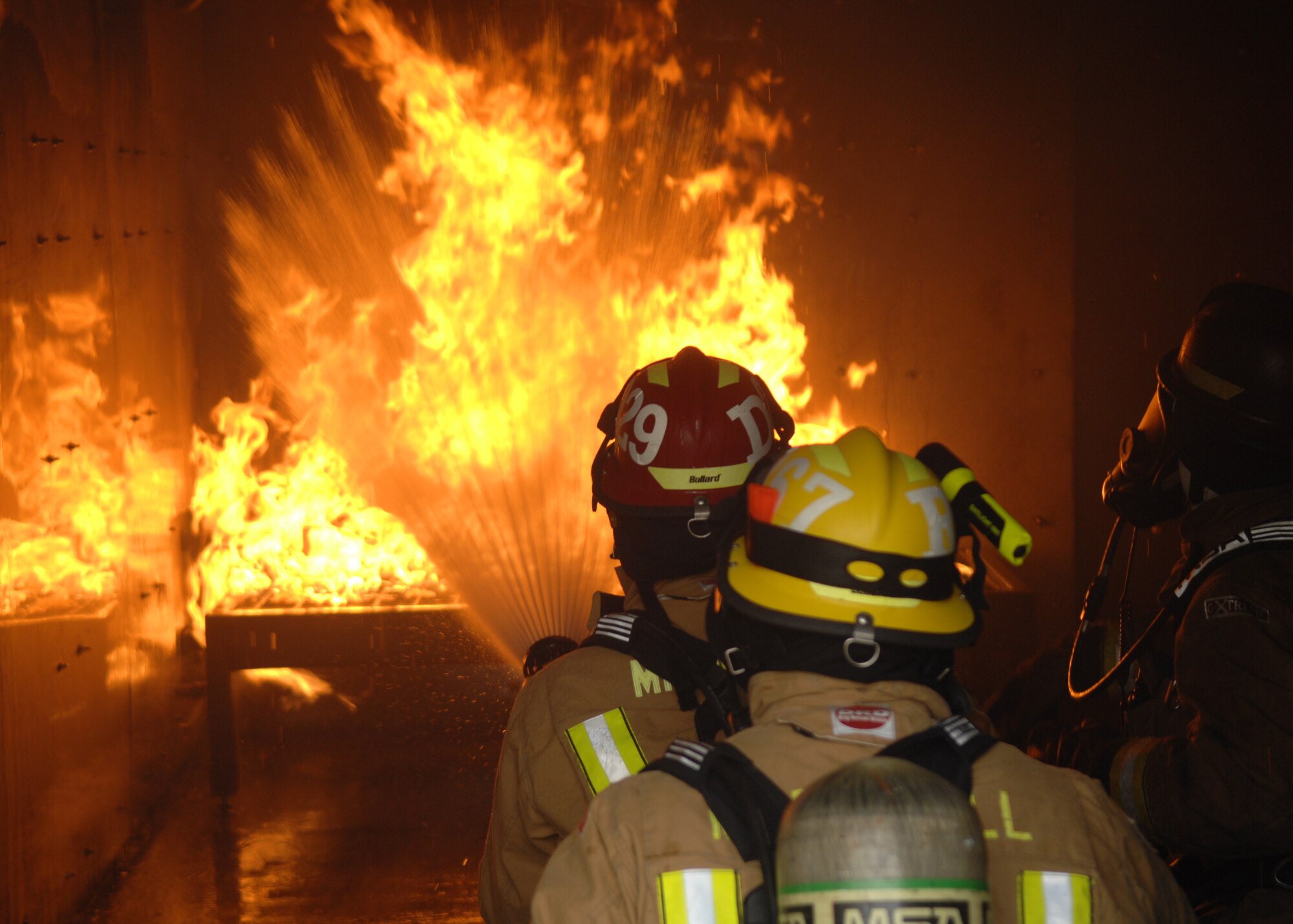 Tech. Sgt. Thomas Doyle from Charlotte, N.C., and Senior Airman Noel Rivera-Saldana from Lake Mary, Fla., both 100th Civil Engineer Squadron Fire Department firefighters, sweep water from a handline over a fire in the structural trainer Feb. 20, 2013, at RAF Mildenhall, England. The firefighters train regularly on structural, aircraft and compartmental fires to ensure a quick and effective response in real-world situations.  (U.S. Air Force photo by Airman 1st Class Dillon Johnston/Released)