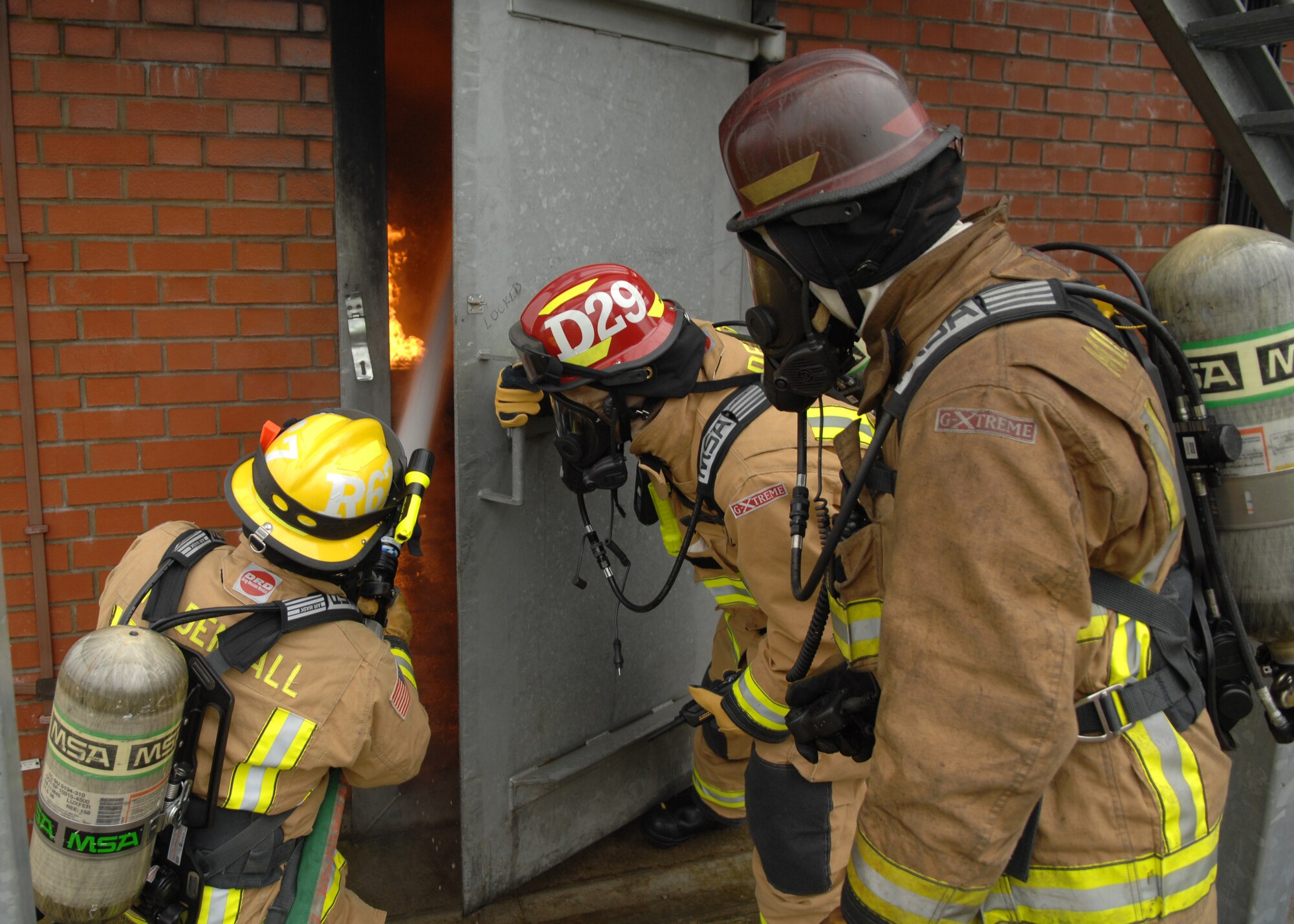 From left, Senior Airman Noel Rivera-Saldana from Lake Mary, Fla.; Tech. Sgt. Thomas Doyle from Charlotte, N.C., and Watch Manager Dave Bootman from Feltwell, Norfolk; 100th Civil Engineer Squadron Fire Department firefighters, practice door procedures before entering a structural trainer Feb. 20, 2013, at RAF Mildenhall, England. The firefighters train regularly on structural, aircraft and compartmental fires to ensure quick and effective response in real-world situations. (U.S. Air Force photo by Airman 1st Class Dillon Johnston/Released)
