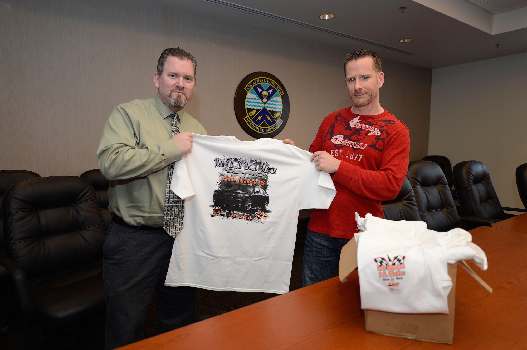 Mr. Bradley Schmidt (right) and Mr. Steven Minard show off the t-shirt design for the upcoming Mid-Atlantic Modern Mopars Fight Against MS car show organized to raise money for Multiple Sclerosis. Schmidt was medically retired after being disgnosed with MS, and he along with Minard have organized the March 16th car show  to raise money for others affected by the disease. Both are shown on Feb. 27, 2013, Dover Air Force Base, Del. (U.S. Air Force photo/Greg L. Davis)