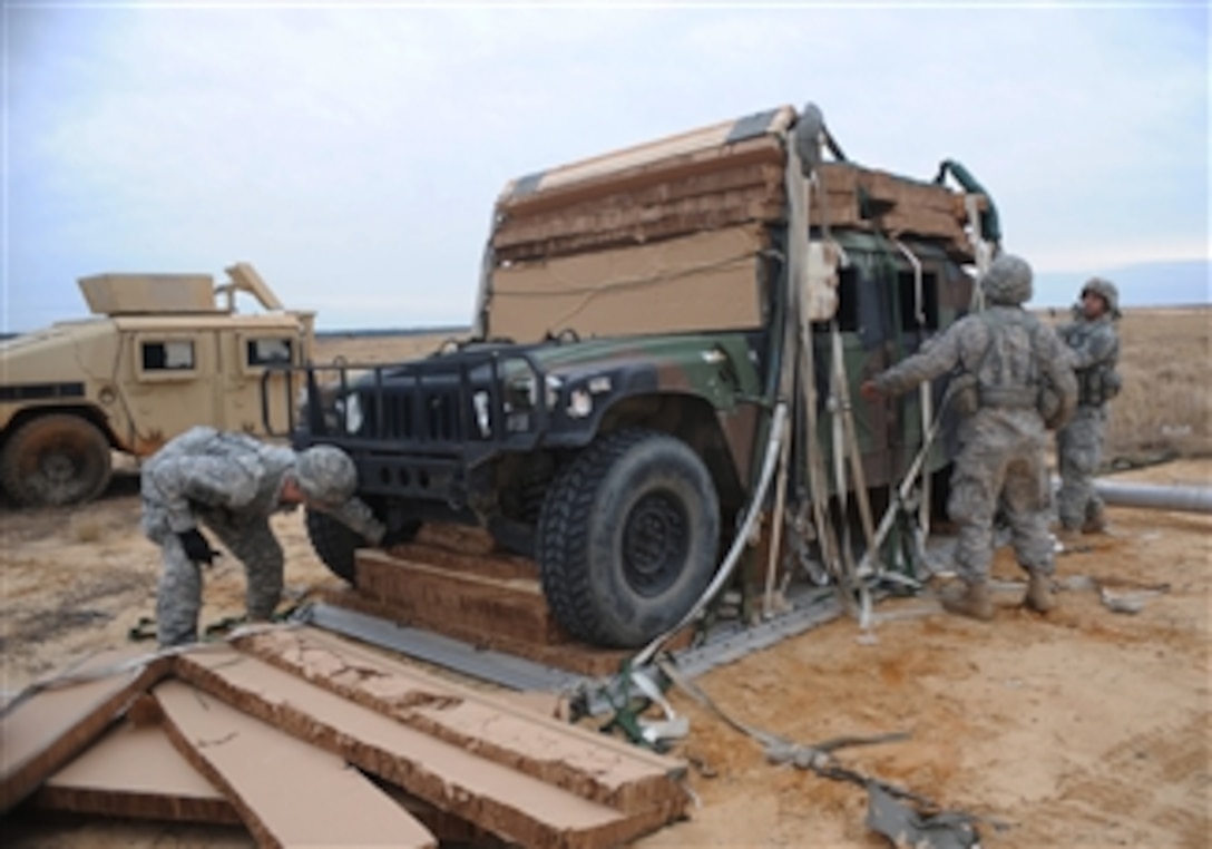 U.S. Army soldiers with the 82nd Airborne Division tear off corrugated box padding from a Humvee that was air dropped during a joint operational access exercise on the Sicily drop zone at Fort Bragg, N.C., on Feb. 25, 2013.  The exercise enhances cohesiveness between U.S. Army, Air Force and allied personnel, allowing the services an opportunity to properly execute large-scale heavy equipment and troop movement. 