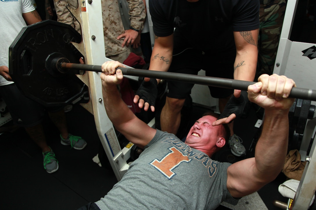 Lance Cpl. Thomas W. Courtney, team leader, 2nd Platoon, Kilo Company, Battalion Landing Team 3/5, 15th Marine Expeditionary Unit, pushes out his final repetition during the Bench Press Competition in the gym of the USS Peleliu, Dec. 29. The challenge was the seventh competition in the Campbell Cup, a bi-monthly challenge that pits teams within the 15th MEU and Peleliu Amphibious Ready Group against each other. The goal was for teams of up five Marines or sailors to do as many bench presses as possible per team member. The 15th MEU is deployed as part of the Peleliu ARG as a U.S. Central Command theater reserve force, providing support for maritime security operations and theater security cooperation efforts in the U.S. 5th Fleet area of responsibility. Courtney, 22, is from Wilmington, Ill. (U.S. Marine Corps photo by Cpl. John Robbart III)
