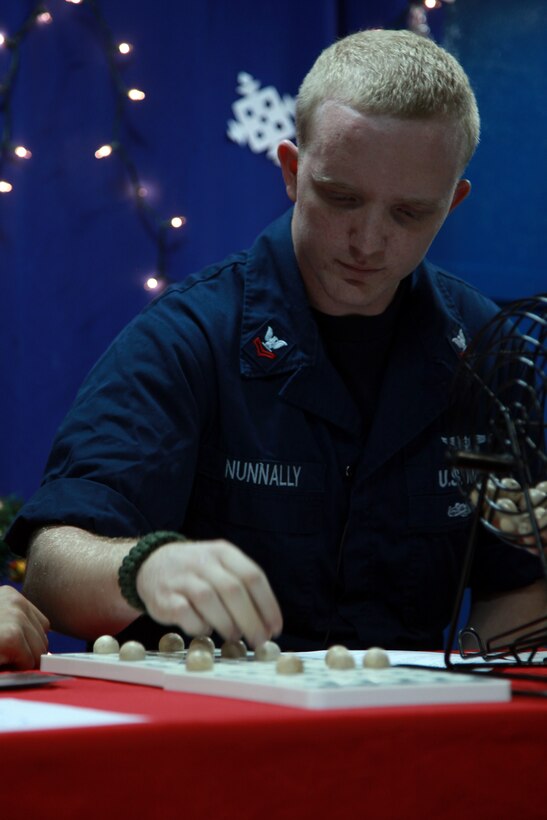 Logistics Specialist 2nd Class Christopher L. Nunnally, USS Peleliu, places a number on a board while taking part in hosting a ship-wide bingo competition aboard the ship, Dec. 18. The 15th MEU is deployed as part of the Peleliu Amphibious Ready Group as a U.S. Central Command theater reserve force, providing support for maritime security operations and theater security cooperation efforts in the U.S. 5th Fleet area of responsibility. Nunnally, 25, is from Kaufman, Texas