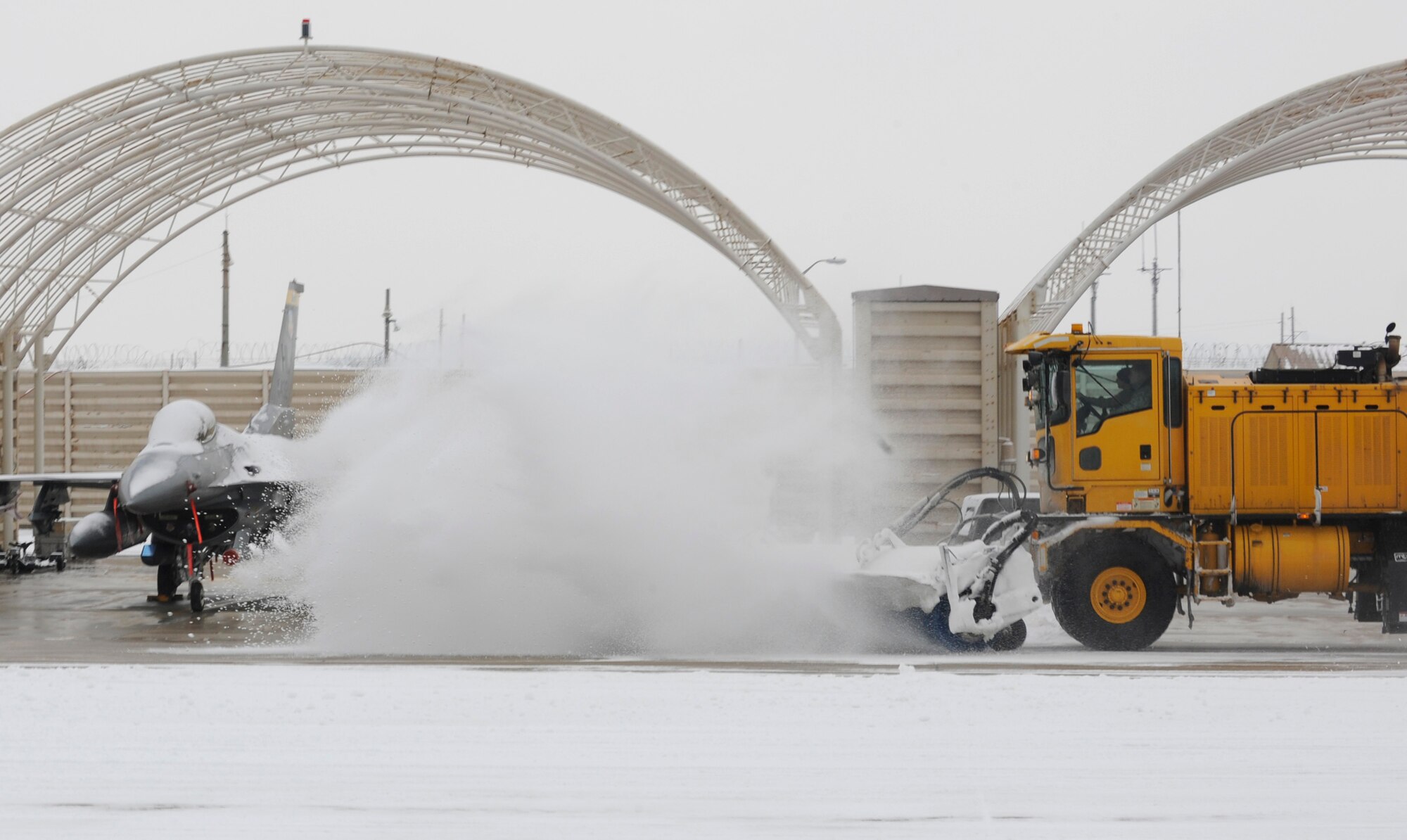 Airmen from the 8th Civil Engineer Squadron clear the taxiway for F-16 Fighting Falcons to take off Dec. 28, 2012, at Kunsan Air Base, Republic of Korea. Although CES is already working 12-hour shifts, their workload increases even more right after a snowfall. (U.S. Air Force photo by Senior Airman Brigitte N. Brantley/Released)