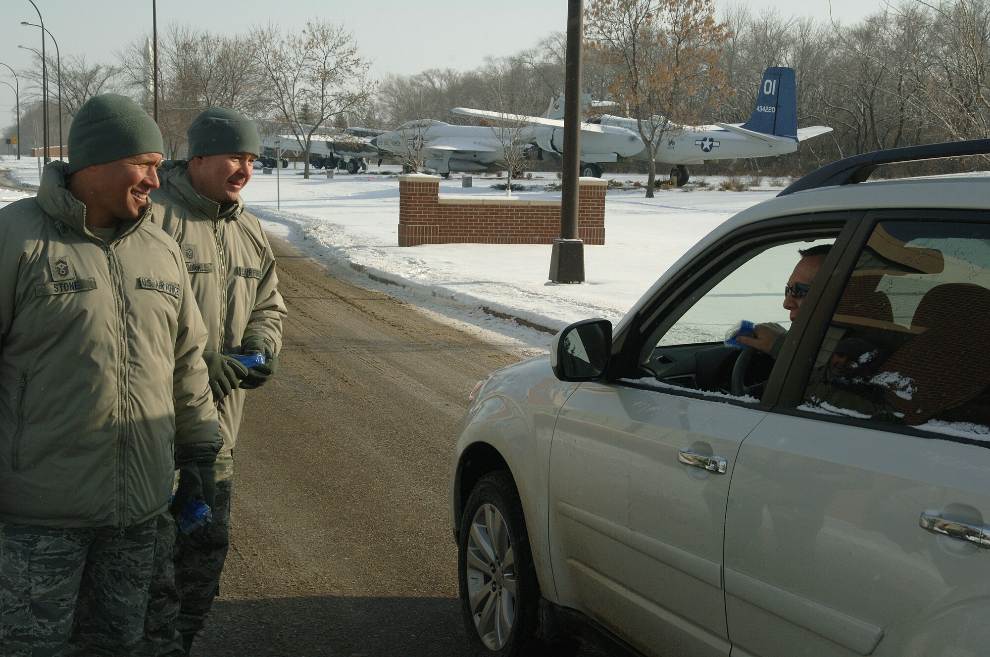Senior Master Sgt. Brian Stone, 69th Reconaissance Group first sergeant, and Master Sgt. Richard McCorkle, 319th Operations Support Squadron first sergeant, hand out Airmen Against Drunk Driving imprinted vehicle ice-scrappers Dec. 28, 2012, on Grand Forks Air Force Base, N.D. AADD raised money throughout 2012 by conduction various fundraisers which helped pay for the ice-scrapers given out that day. (U.S. Air Force photo/Airman 1st Class Zachiah Roberson)