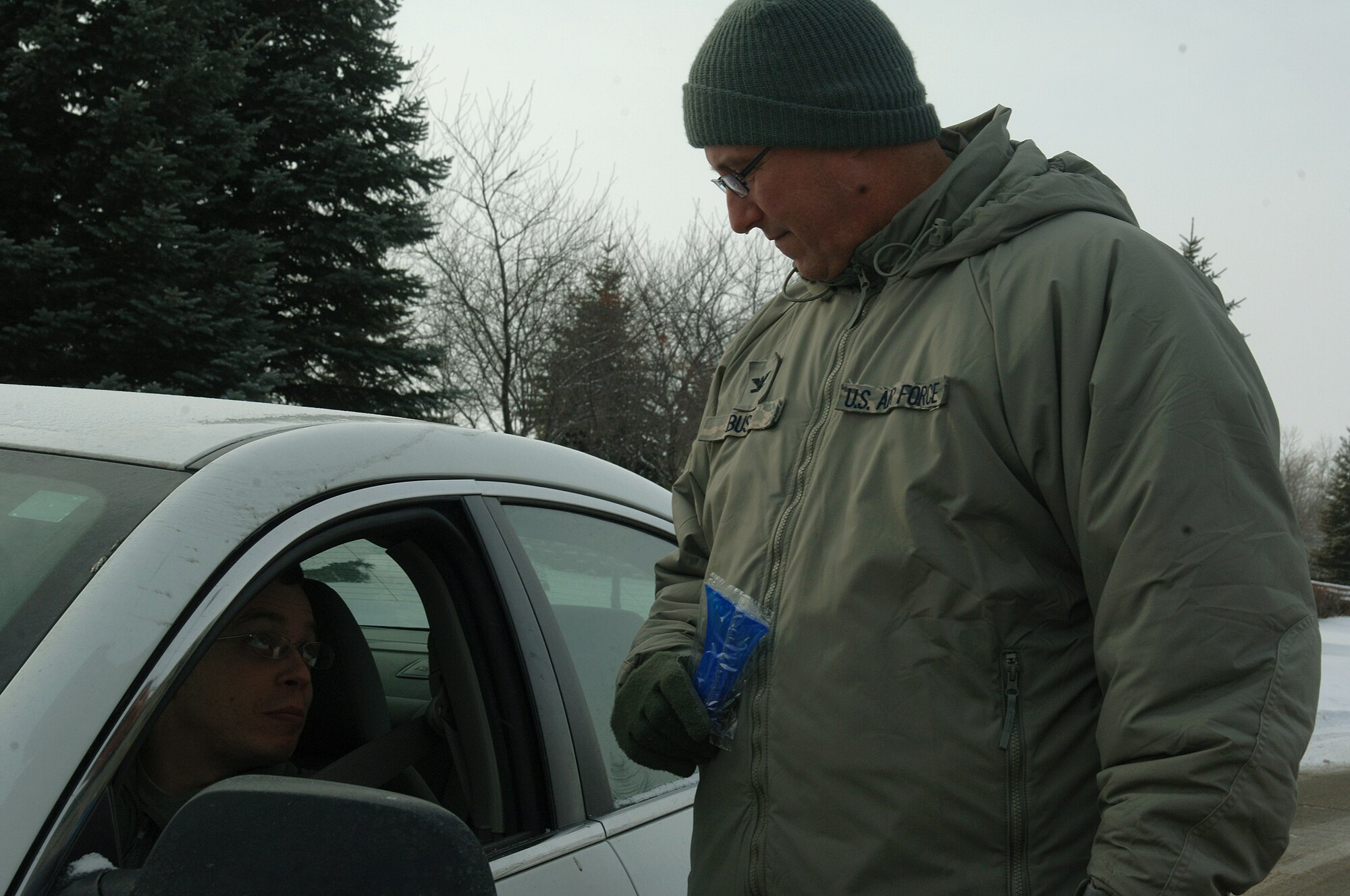 Col. Tim Bush, 319th Air Base Wing commander, talks to Airmen about the dangers of drunk driving and what the Airmen Against Drunk Driving program has to offer Dec. 28, 2012, as they leave Grand Forks Air Force Base, N.D.  AADD raised money throughout 2012 by conducting various fundraisers which helped pay for vehicle ice-scrapers given out that day. (U.S. Air Force photo/Airman 1st Class Zachiah Roberson)