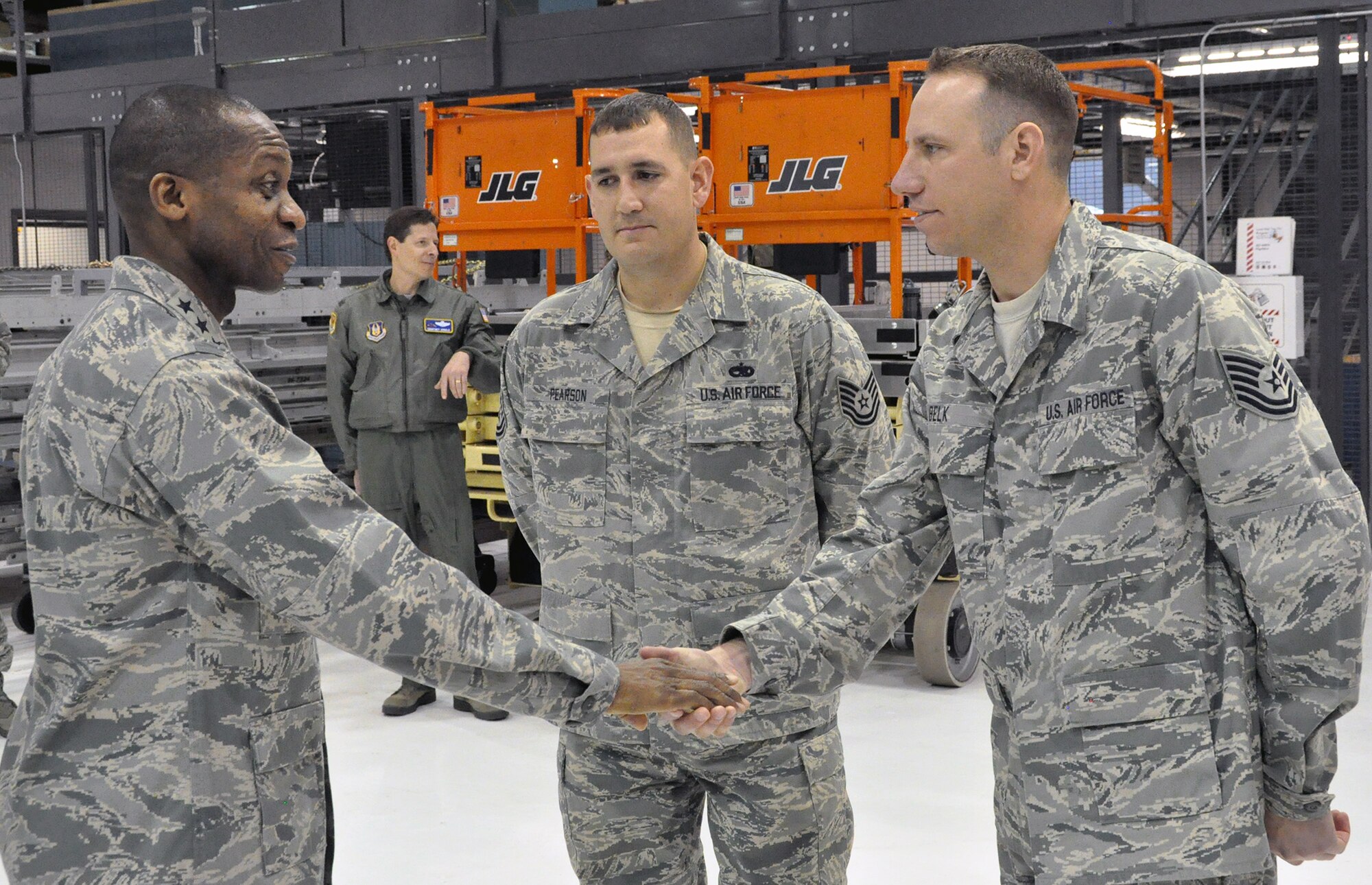 PETERSON AIR FORCE BASE, Colo. – Lt. Gen. Darren McDew, left, 18th Air Force commander, “coins” Tech. Sgt. Daniel Belk, 302nd Airlift Wing C-130 crew chief, here Dec. 19, as Tech. Sgt. Stephen Pearson, 52nd Airlift Squadron C-130 crew chief looks on. The general visited the 302nd AW to observe first-hand the Total Force Integration between the active duty 52nd Airlift Squadron and the reserve wing here. During his all-call, the general challenged Airmen not to “… become numb to the fact you are special." (U.S. Air Force photo/Tech. Sgt. Daniel Butterfield)