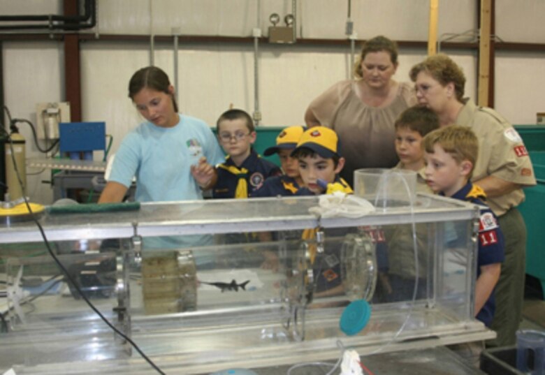 Student researcher Elizabeth Rayfield (left), a sophomore at Mississippi State University, shows scouts and leaders how the endurance of juvenile paddlefish is measured.