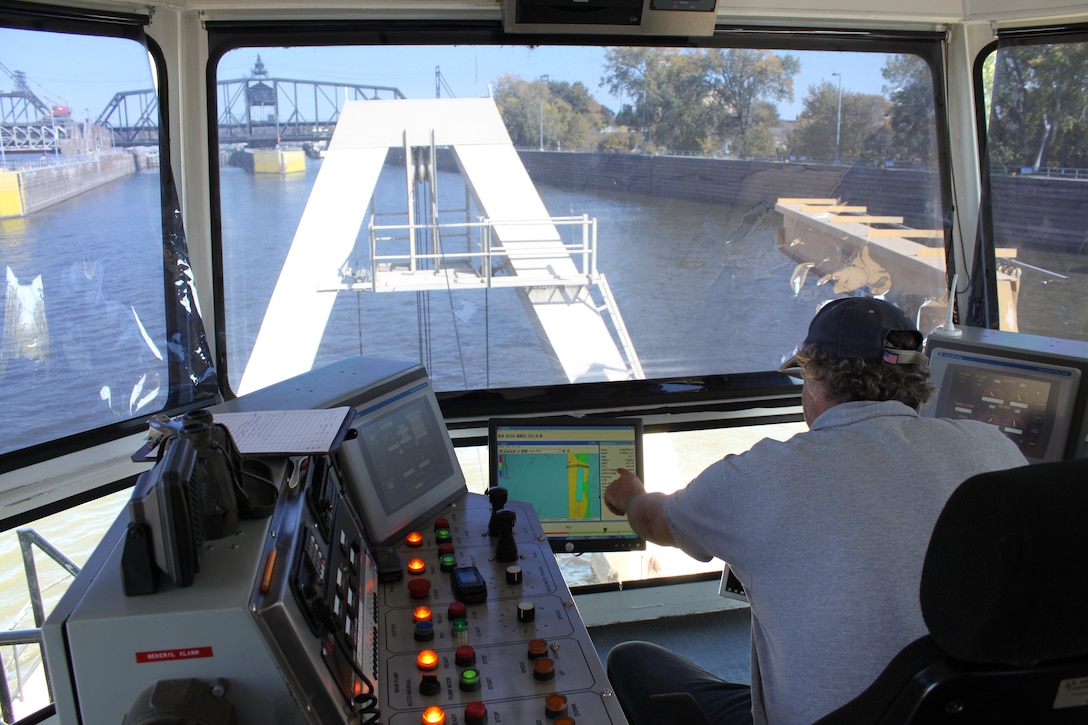 Eric Carlson, a leverman (dredge operator) for St. Paul District's Dredge Goetz, points to the screen showing the dredge cuts prepared by the Rock Island District as he maneuvers the dredge's cutter head into position.